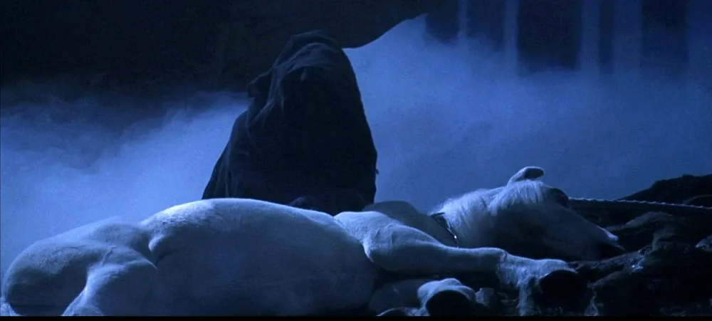 Voldemort in his weakened, pale infant-like form lying under a cloak in a dark, misty scene from Harry Potter.