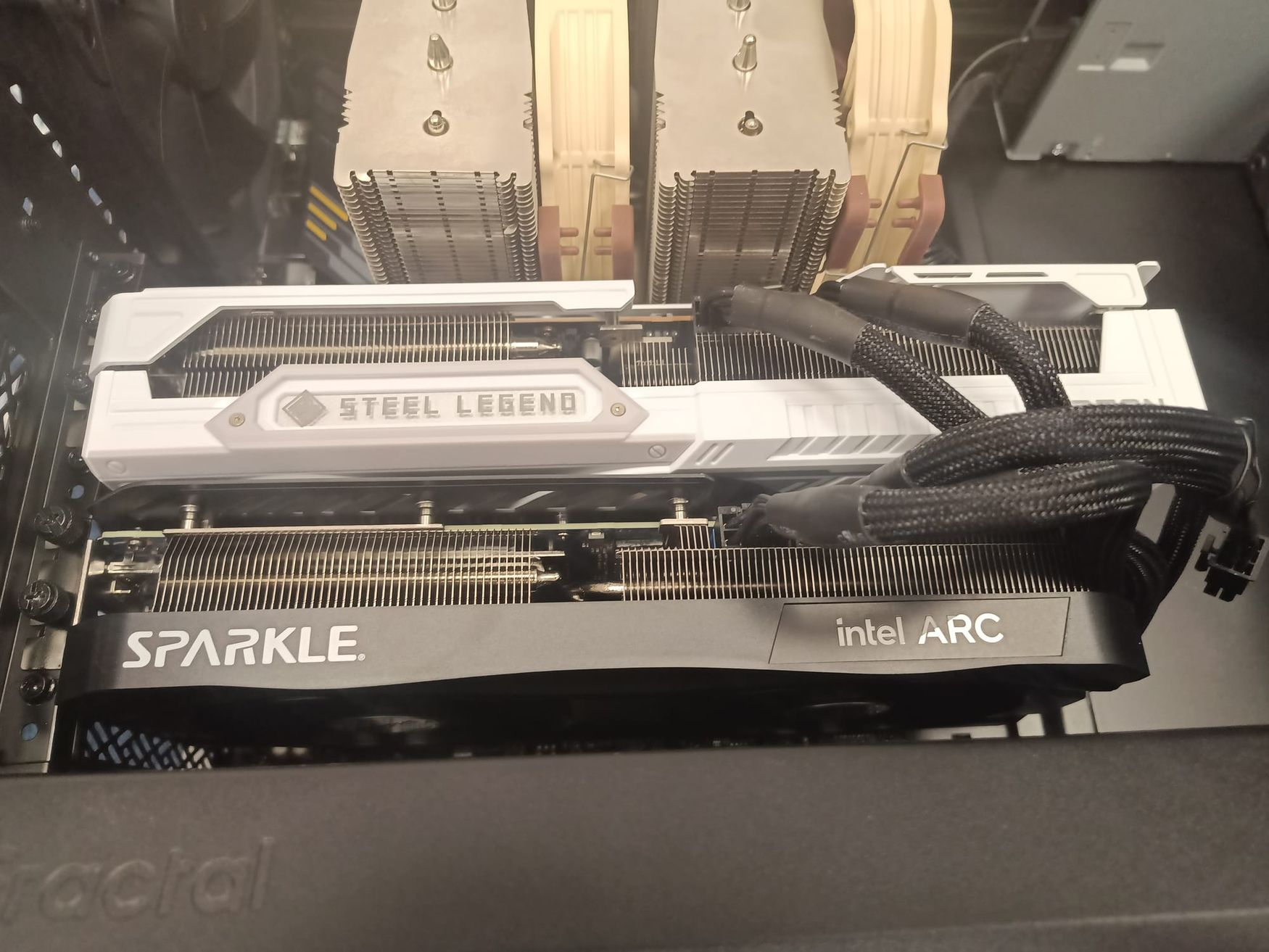 Intel Arc graphics card installed inside a desktop computer alongside a larger primary GPU.