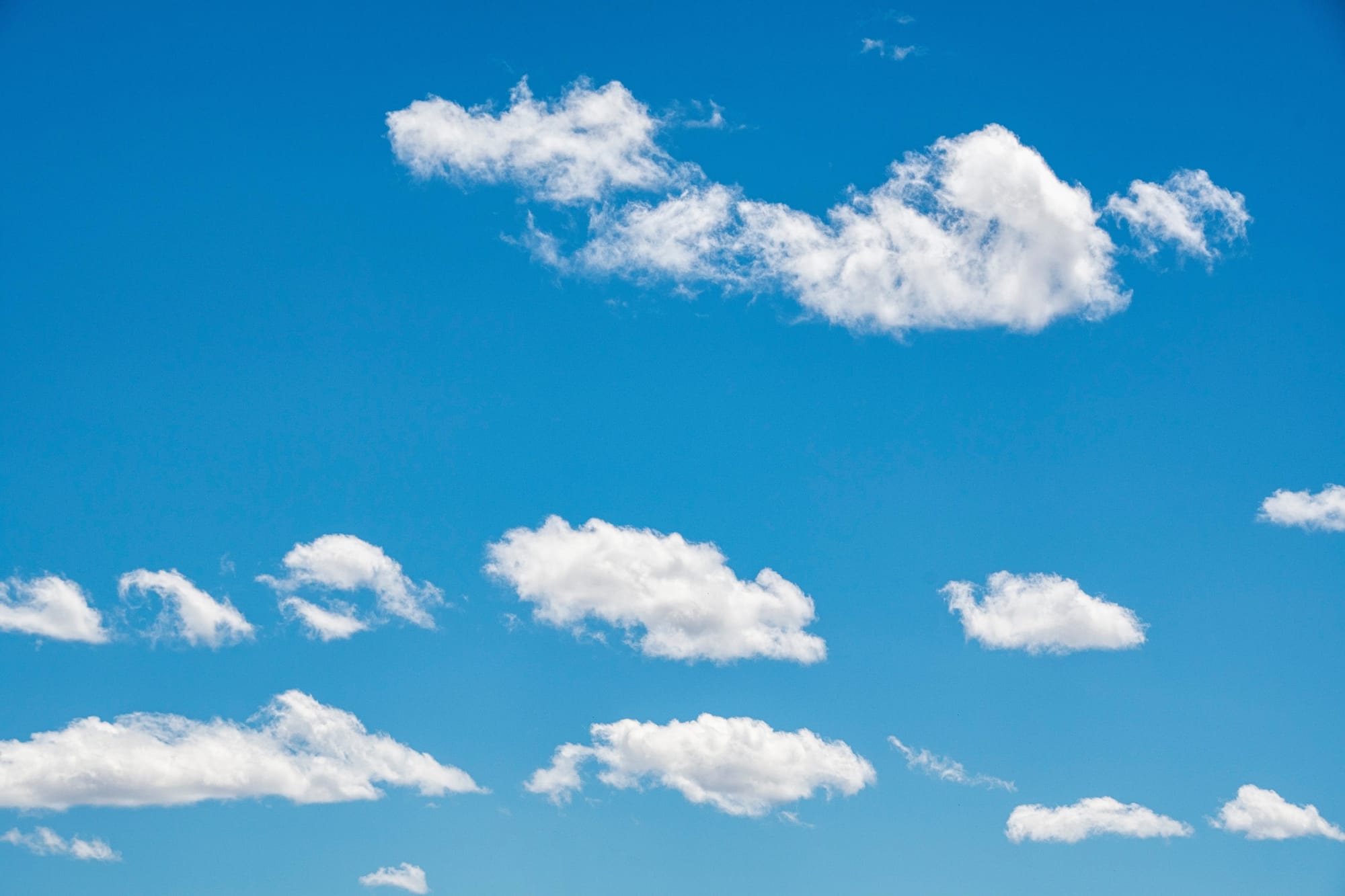Scattered white clouds floating across a bright blue sky.