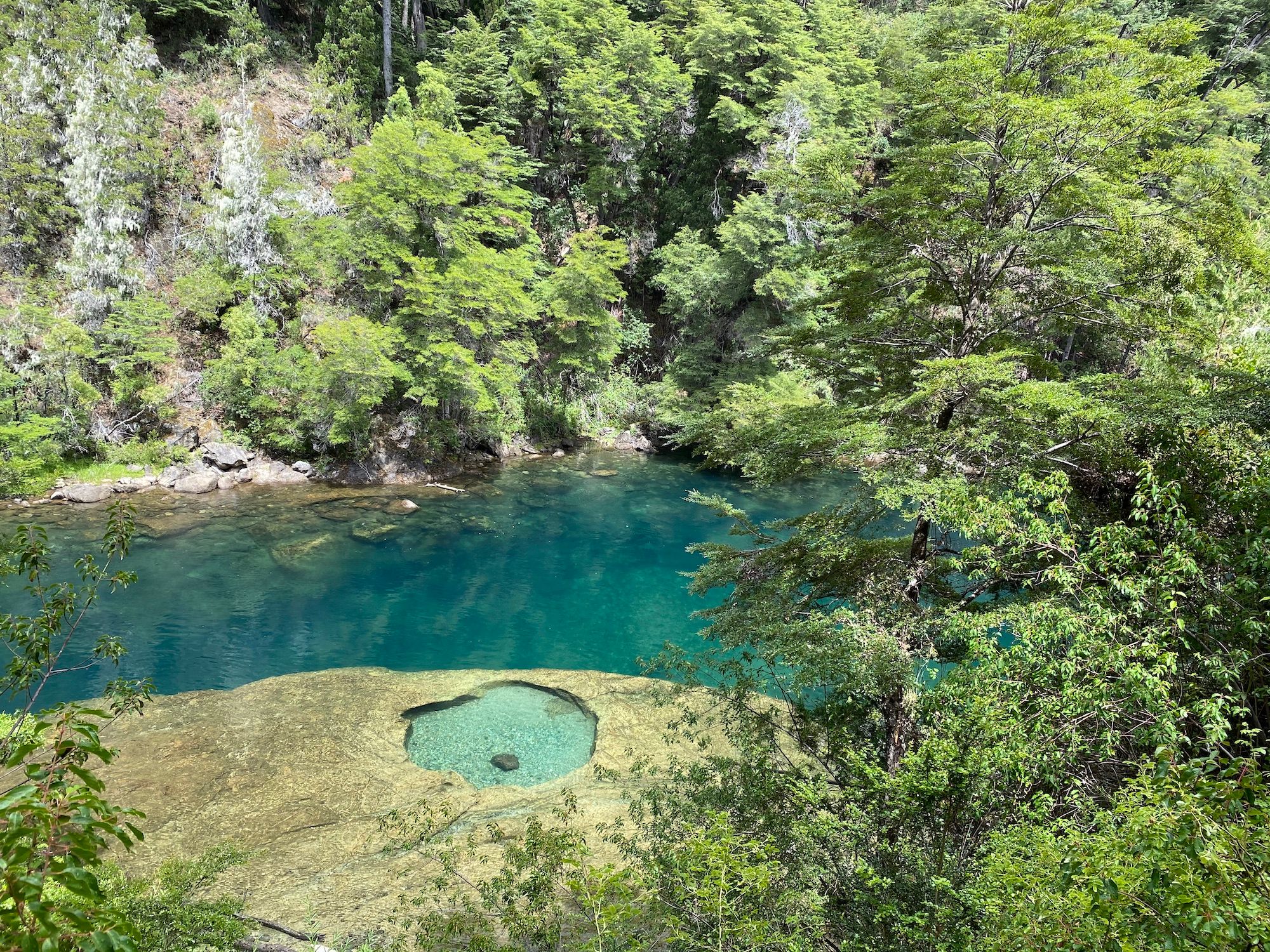 A blue river with a hole carved by a rock
