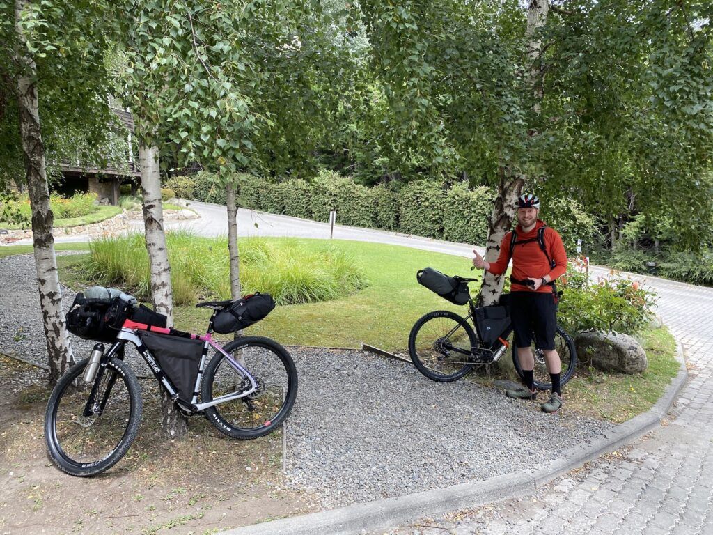 Two bikes leaning against trees and a man giving a thumbs up