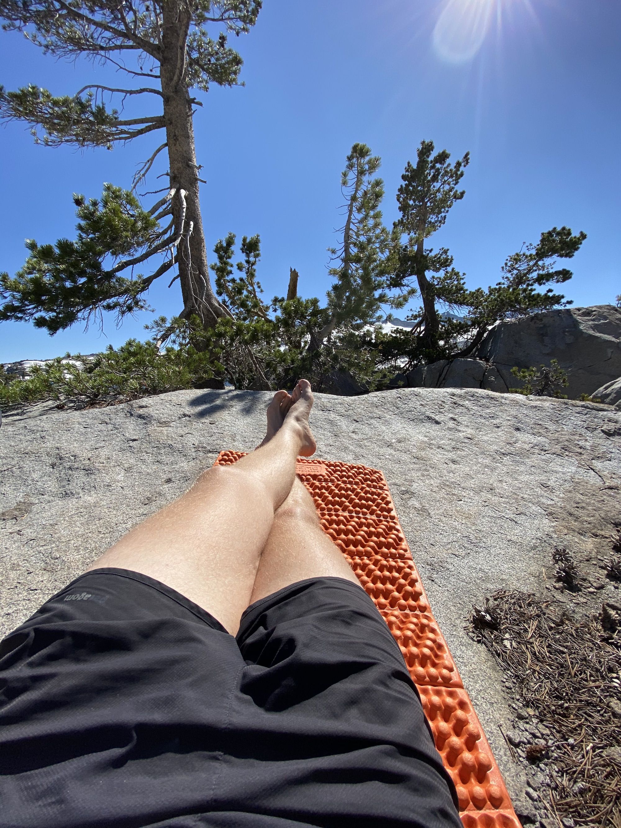 A man's legs on a sleeping pad in the sun