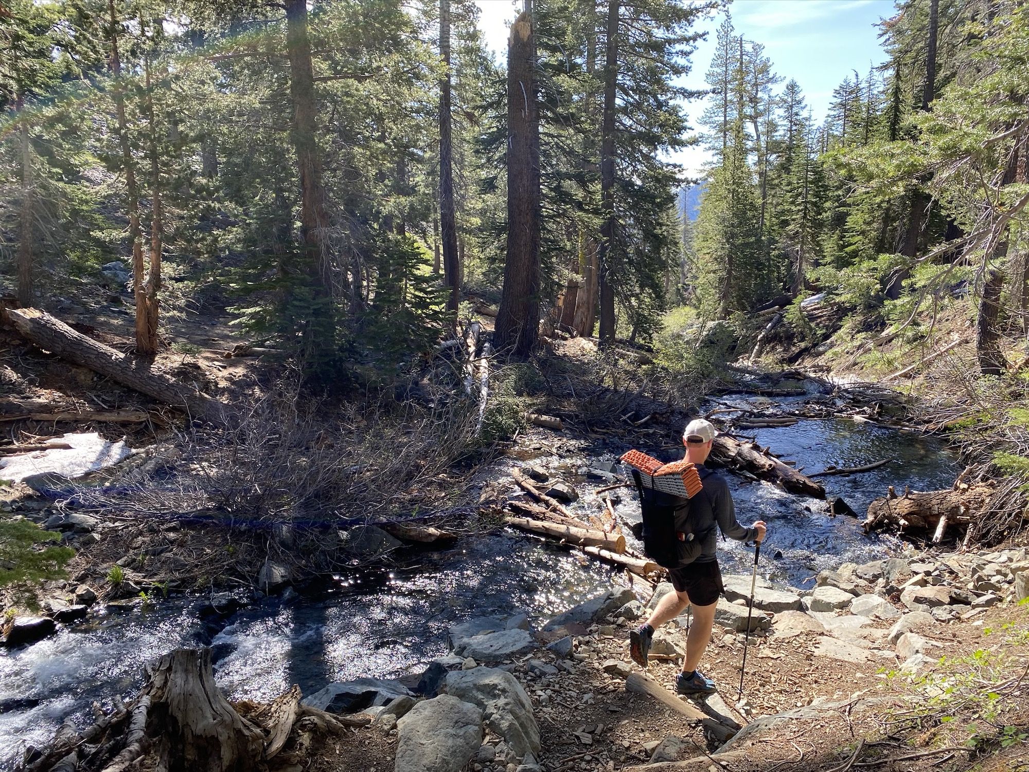 A man with a backpack walking towards a creek