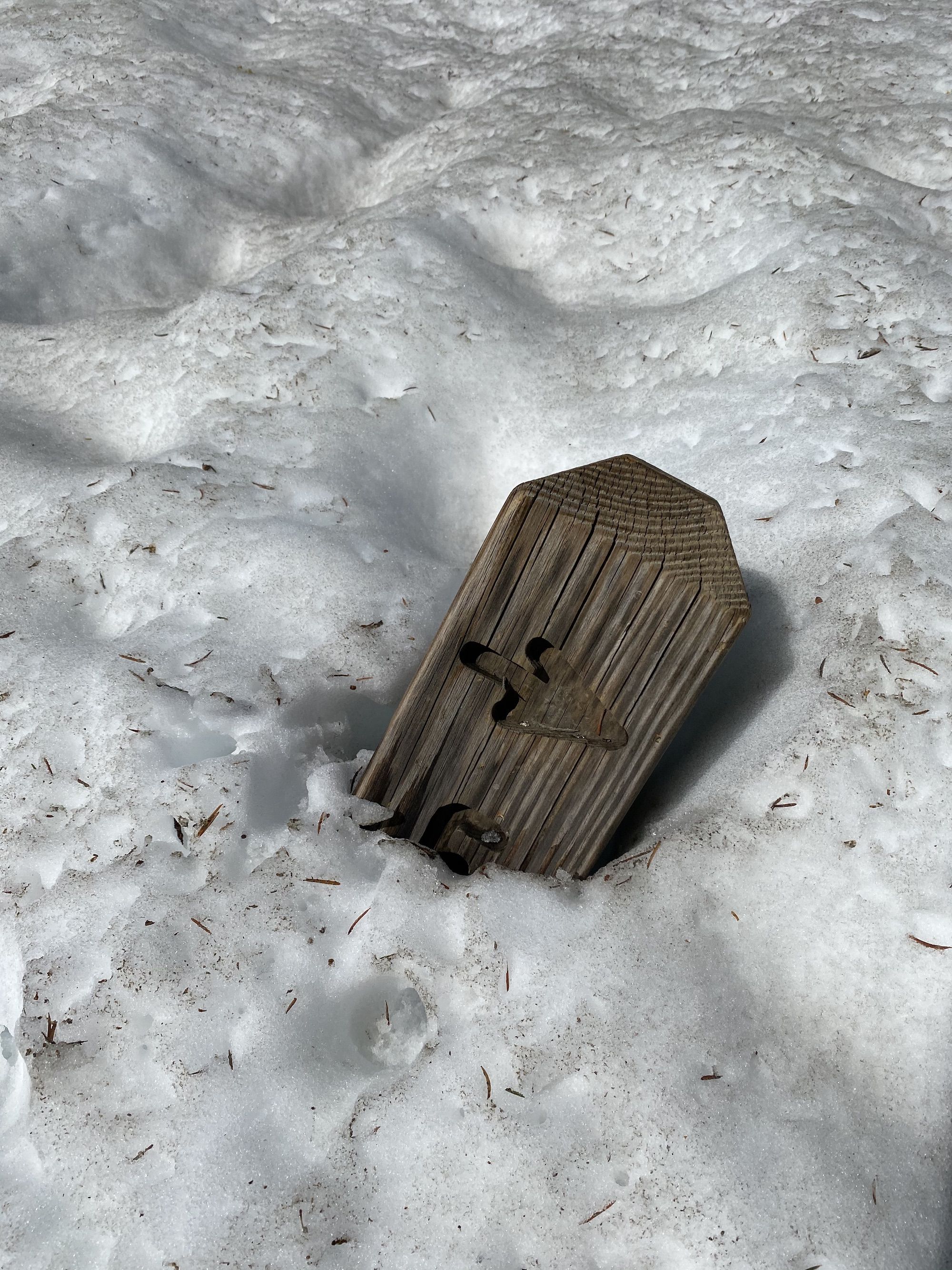 A trail signpost covered sticking out through snow