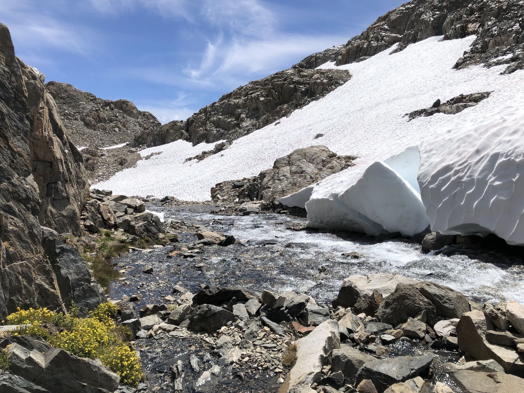 A path that goes through a small stream with blocks of drift snow falling on the side