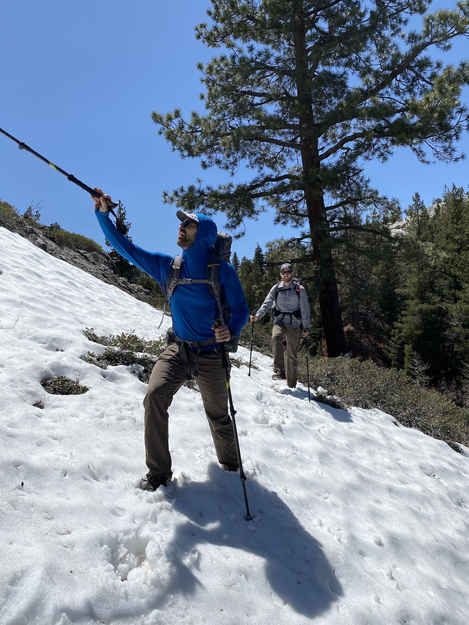 Two backpackers walking on a snowy slope.