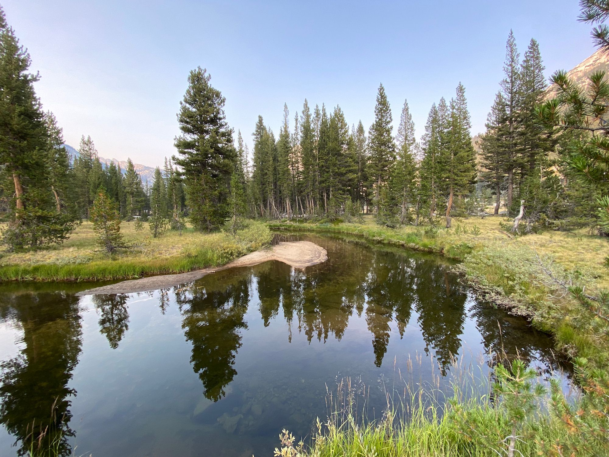 A calm river bend with vegetated riverbanks.