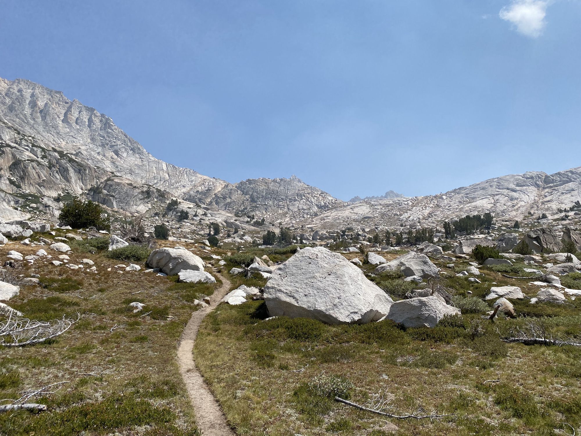 A trail heading up a pass, weaving around rocks.