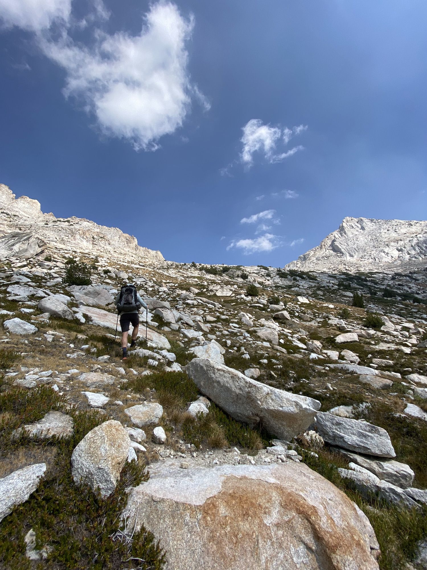 A man walking up steep tundra.