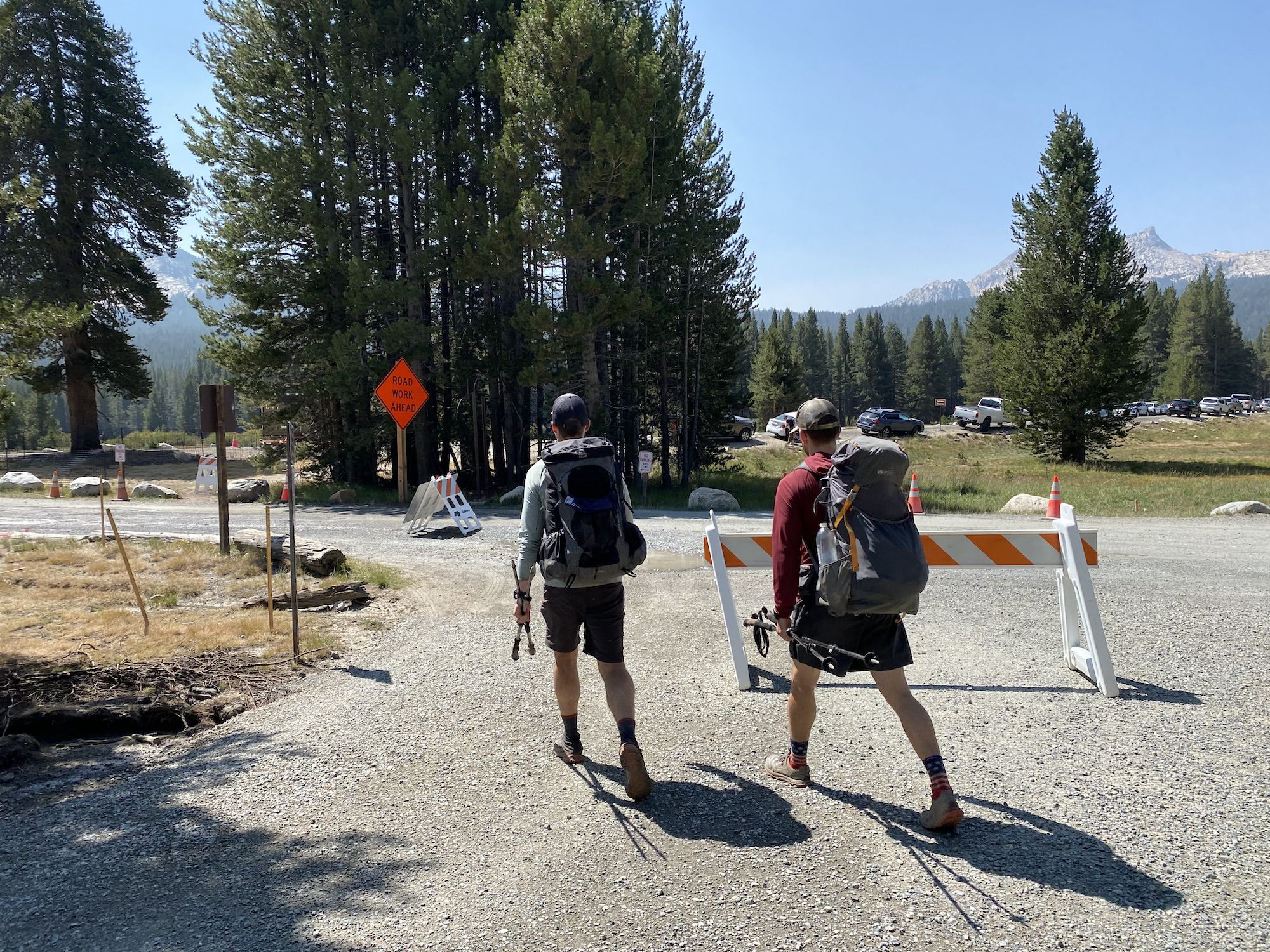 Two backpackers walking past a road work sign.