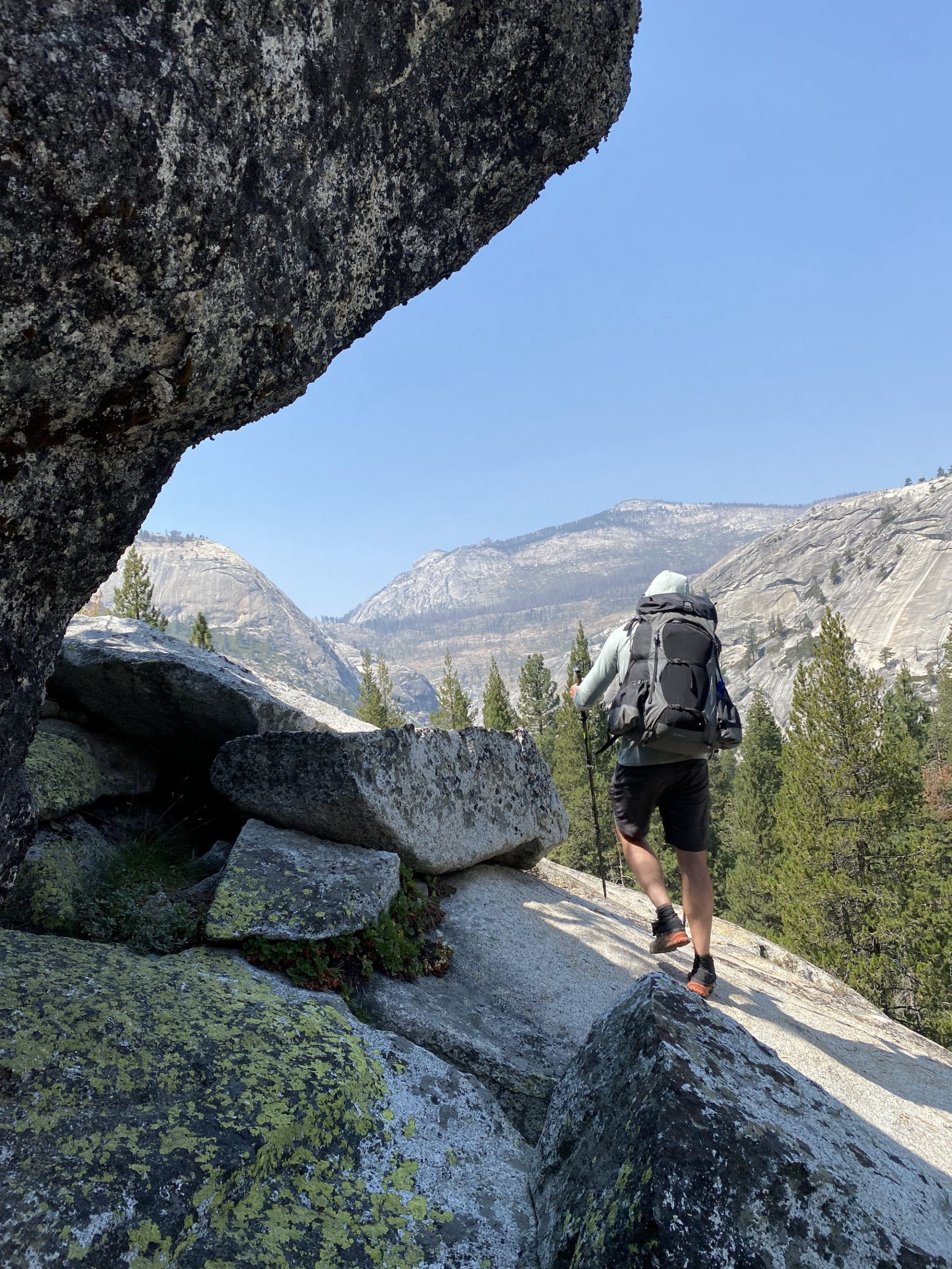 A backpacker on a slanting granite slab.