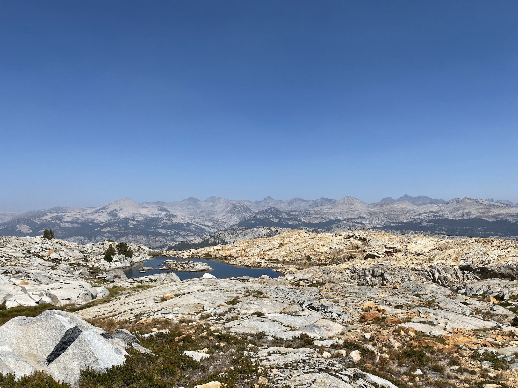 A rugged, rocky mountain landscape with a small lake in the foreground.