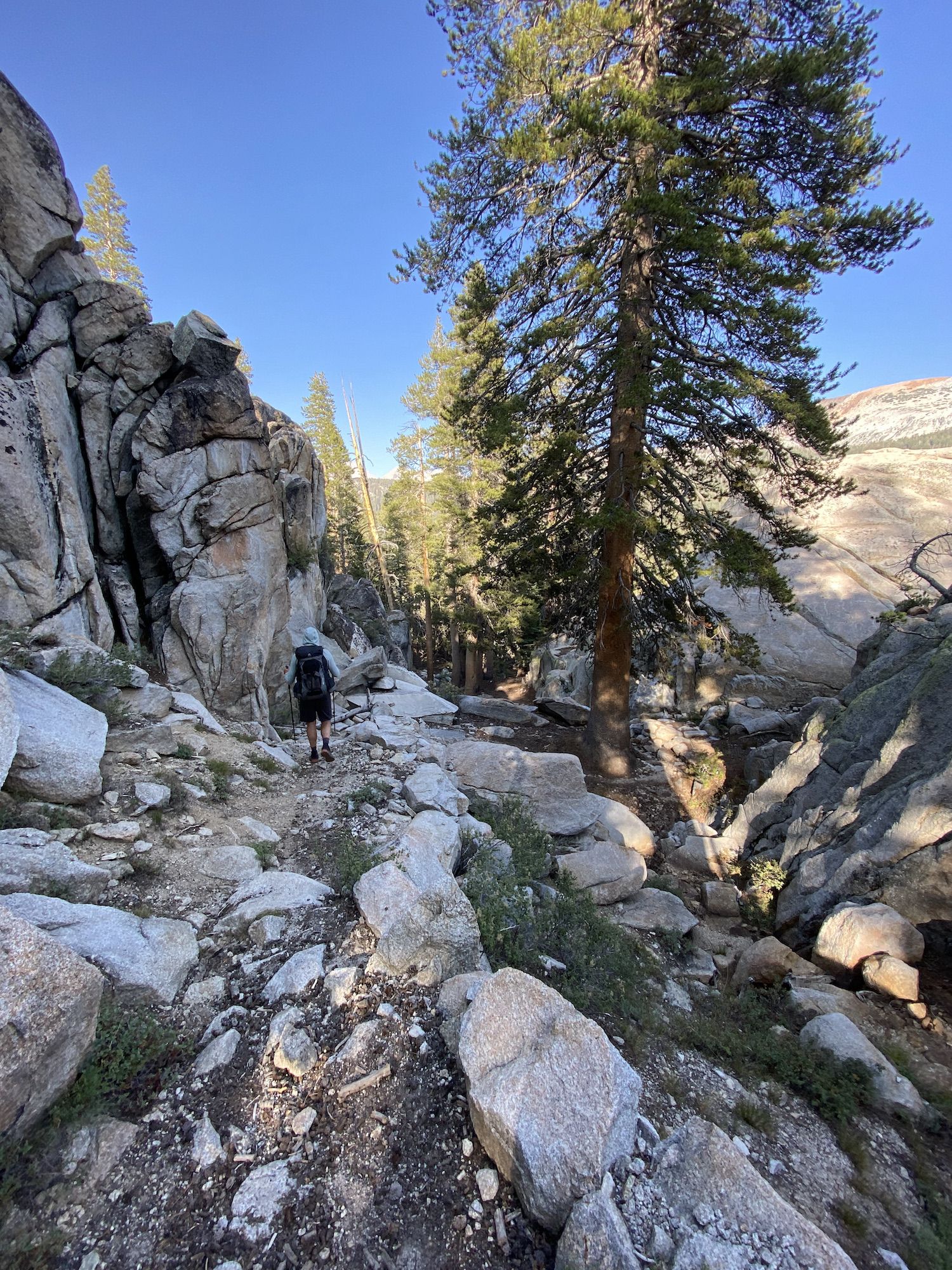 A backpacker walking down a narrow gorge between large boulders.
