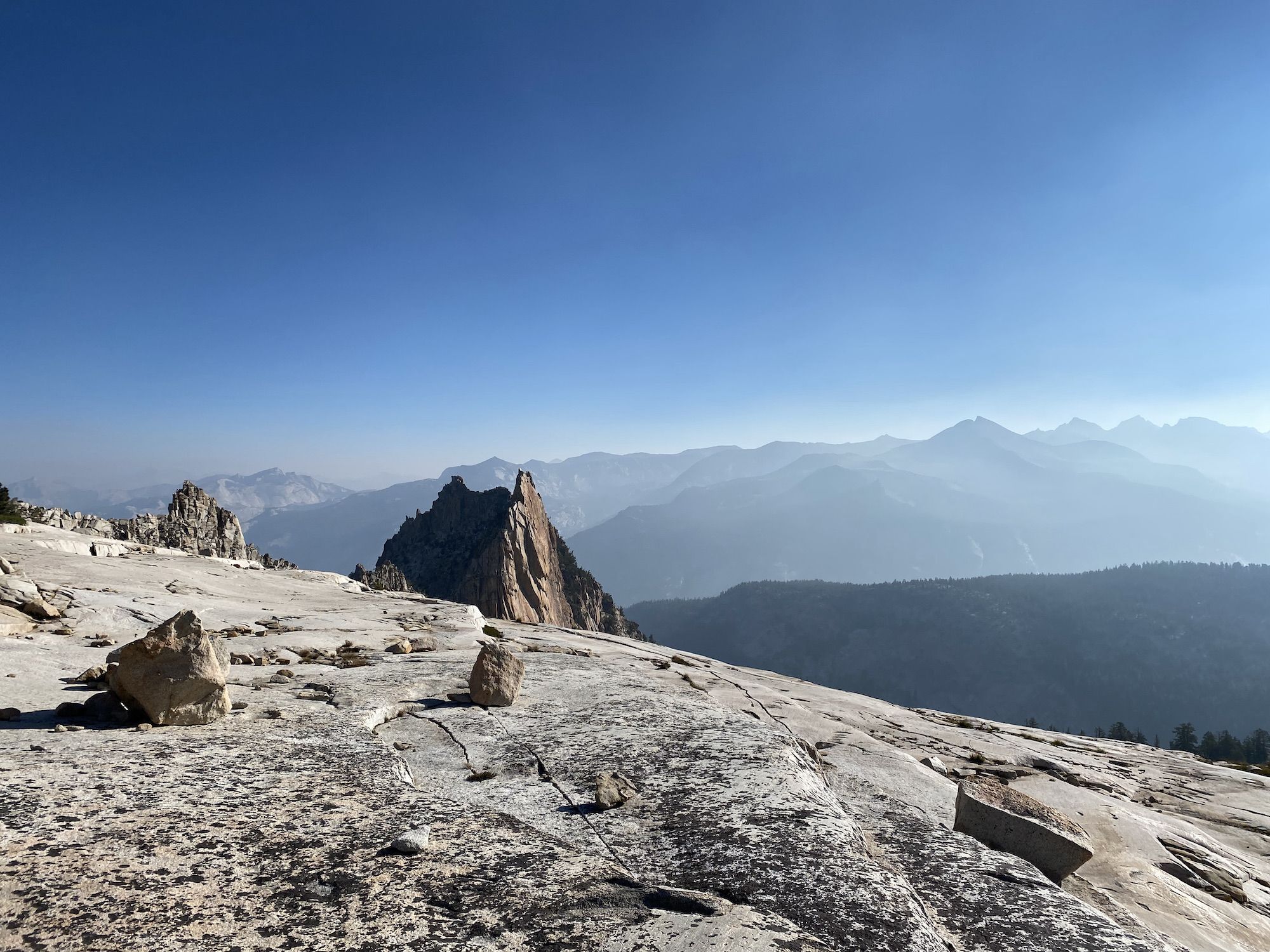 A rocky mountain peak protruding behind a smooth granite slab.