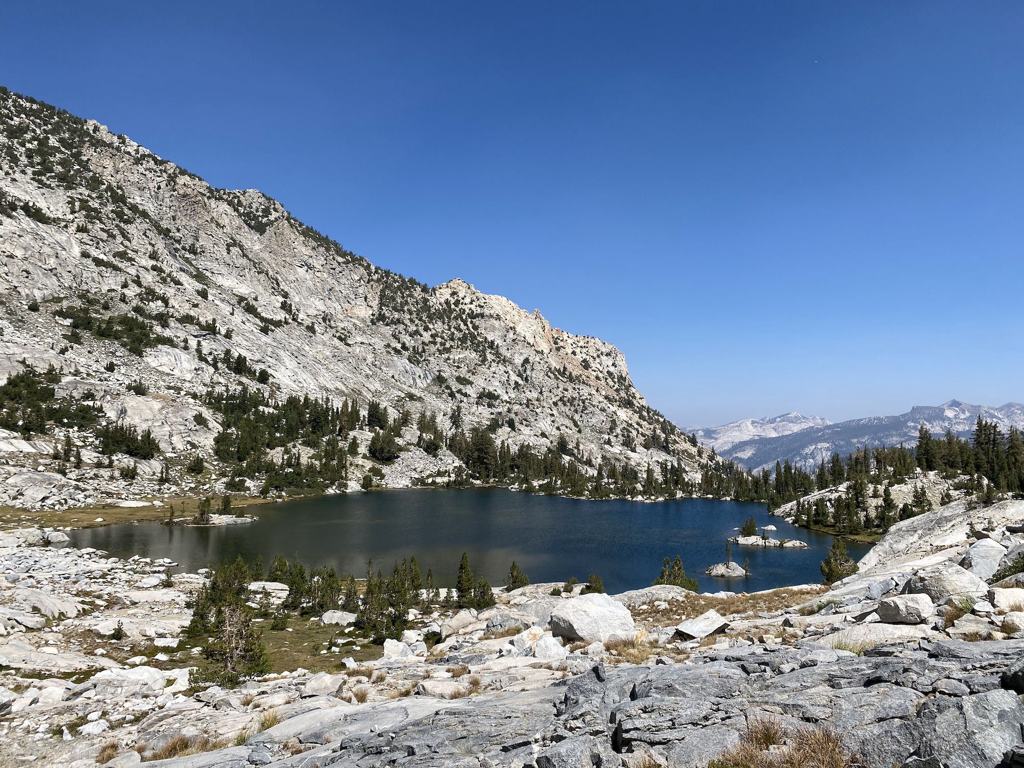 A mountain lake with a steep rocky wall on the opposite side. 