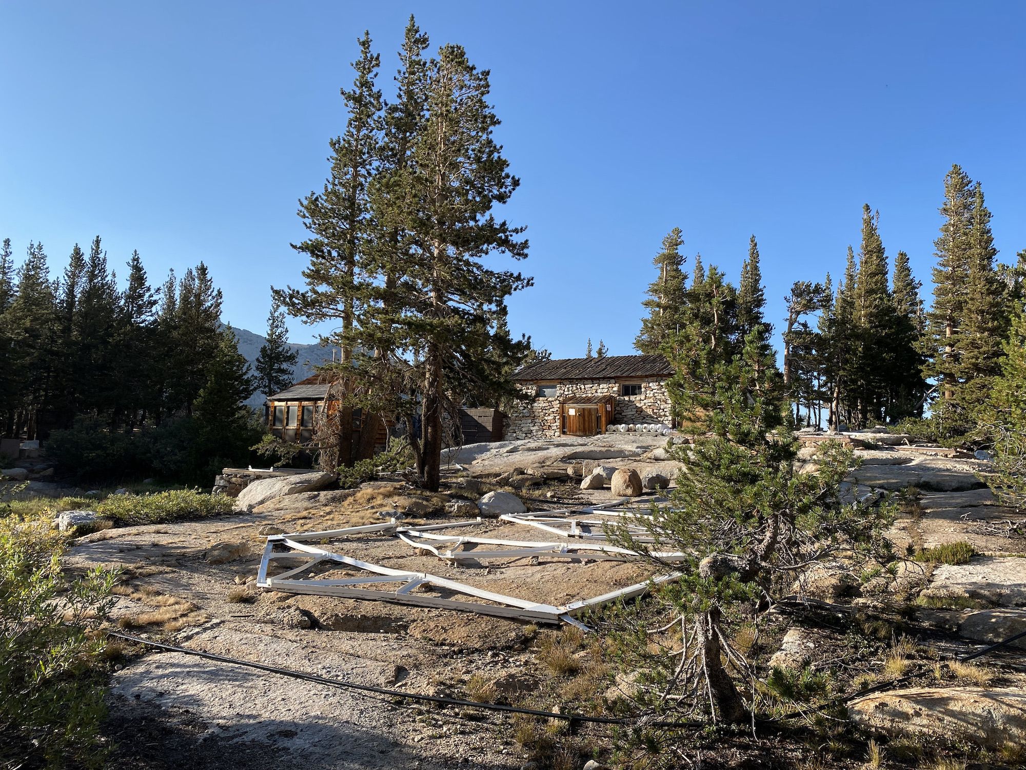 A rock building with tent cabin frames on the ground in the foreground.