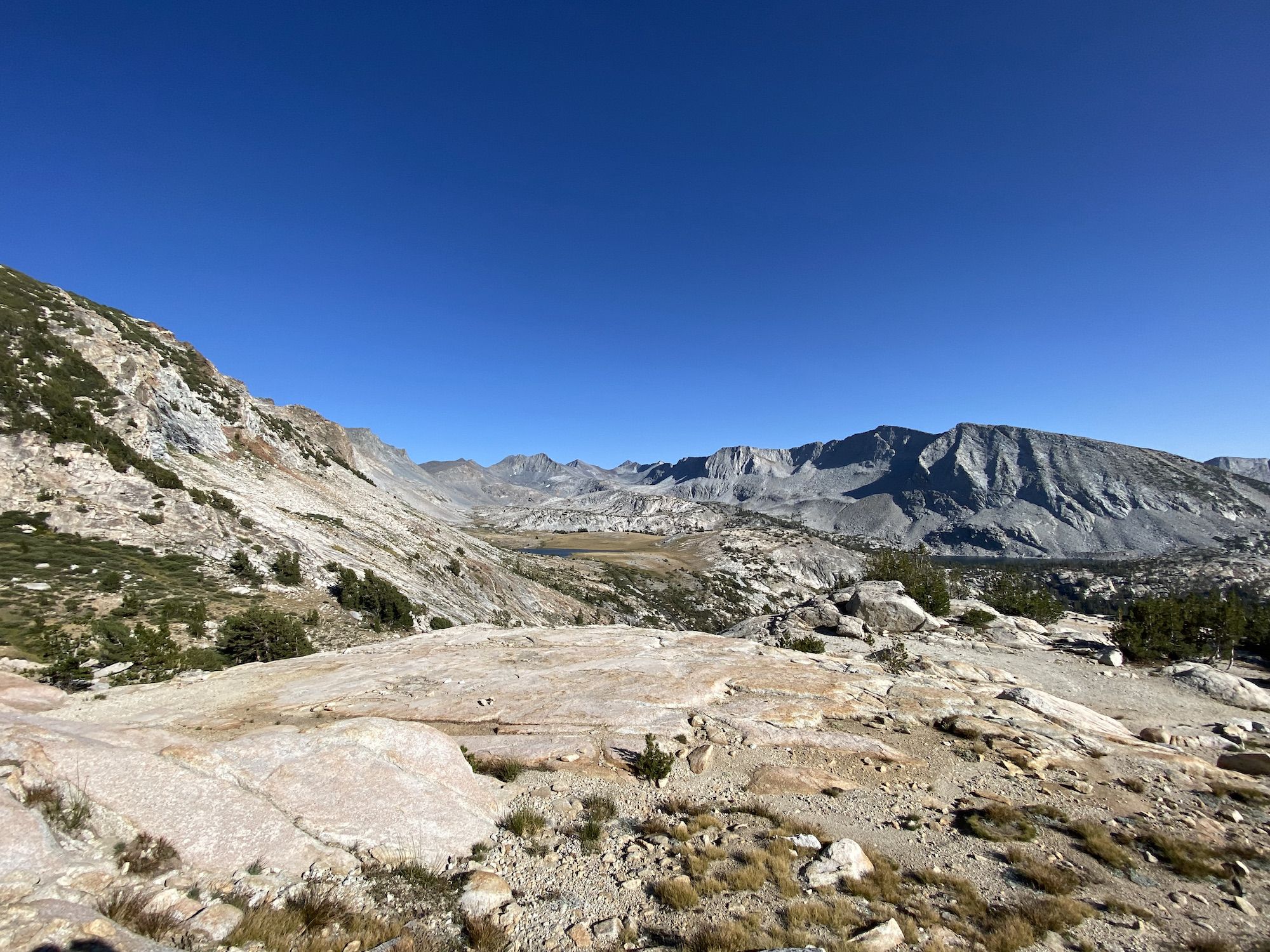 A rocky landscape with little vegetation, a small lake visible in the distance.