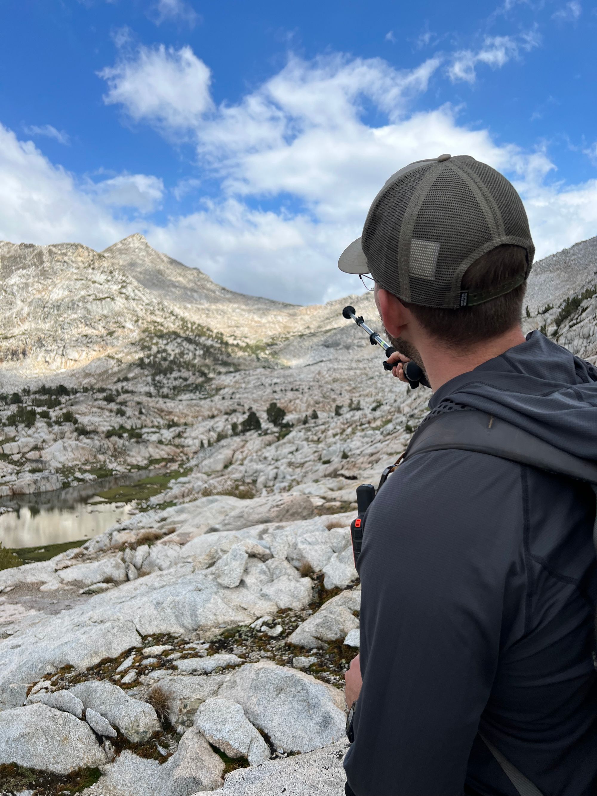 A man pointing at a mountain pass with a trekking pole.