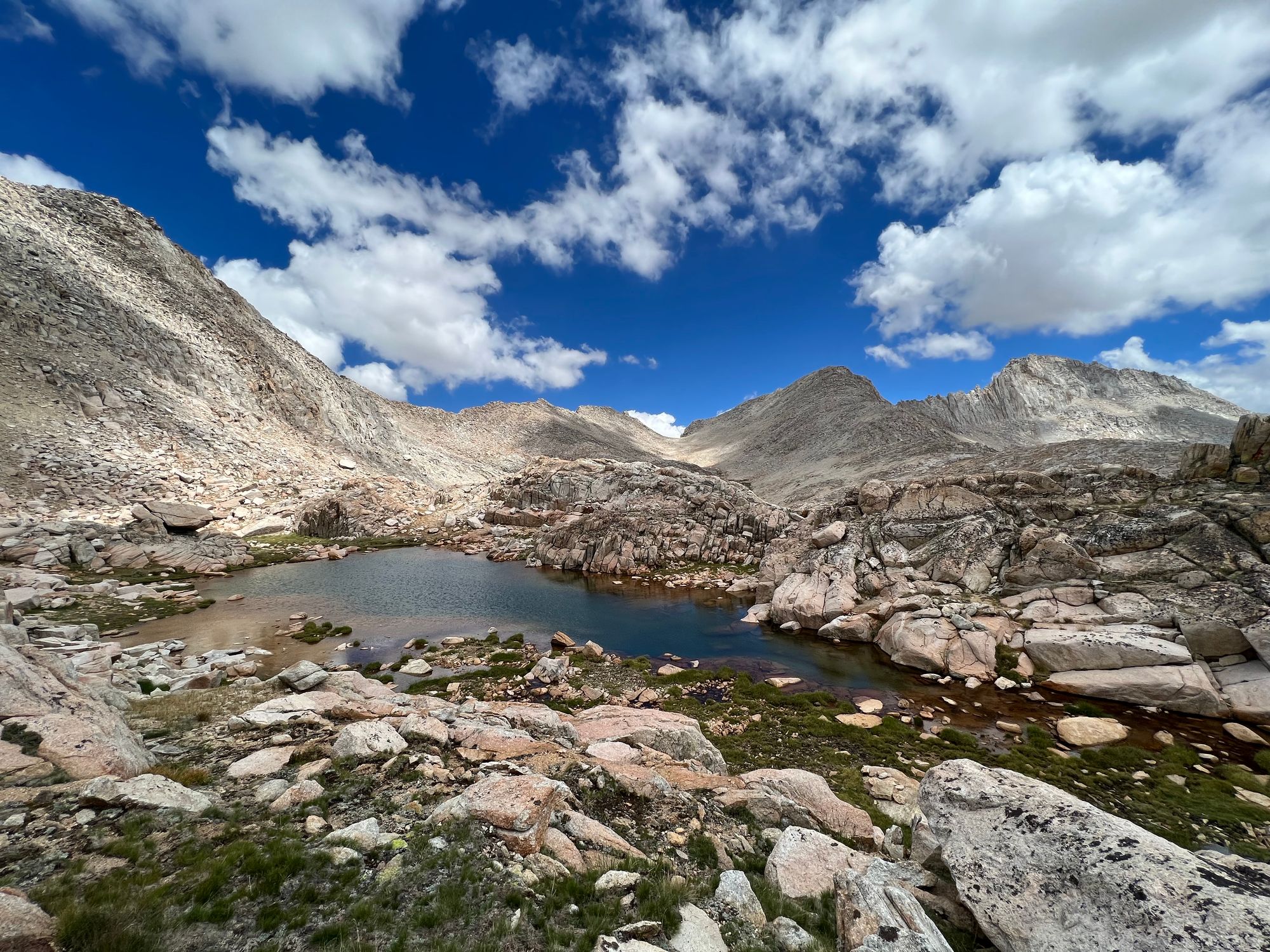 A small pond in the foreground. Bare, rocky mountains on all sides.