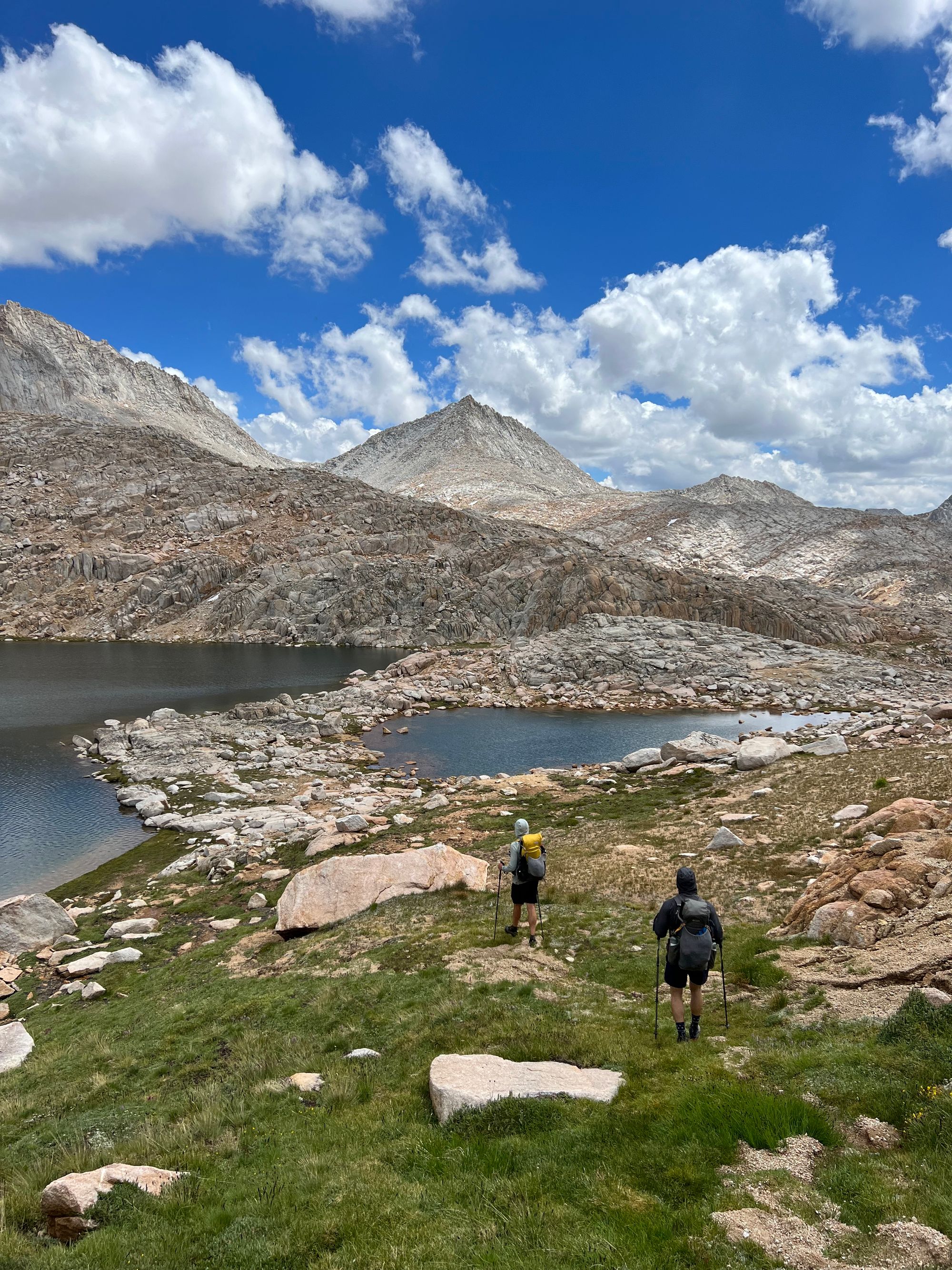 Two backpackers walking along a lake.
