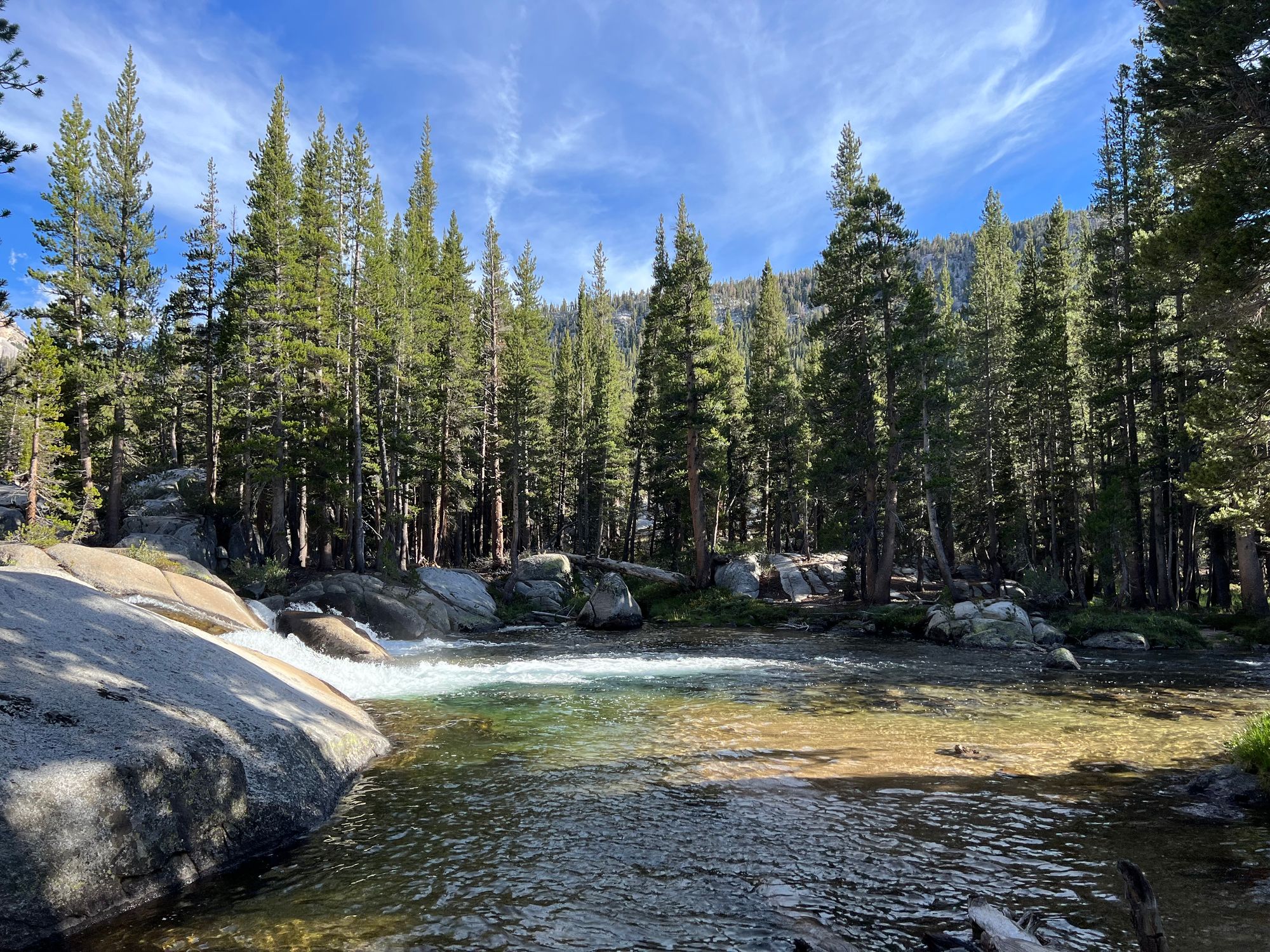 A creek flowing over granite into a deep pool.
