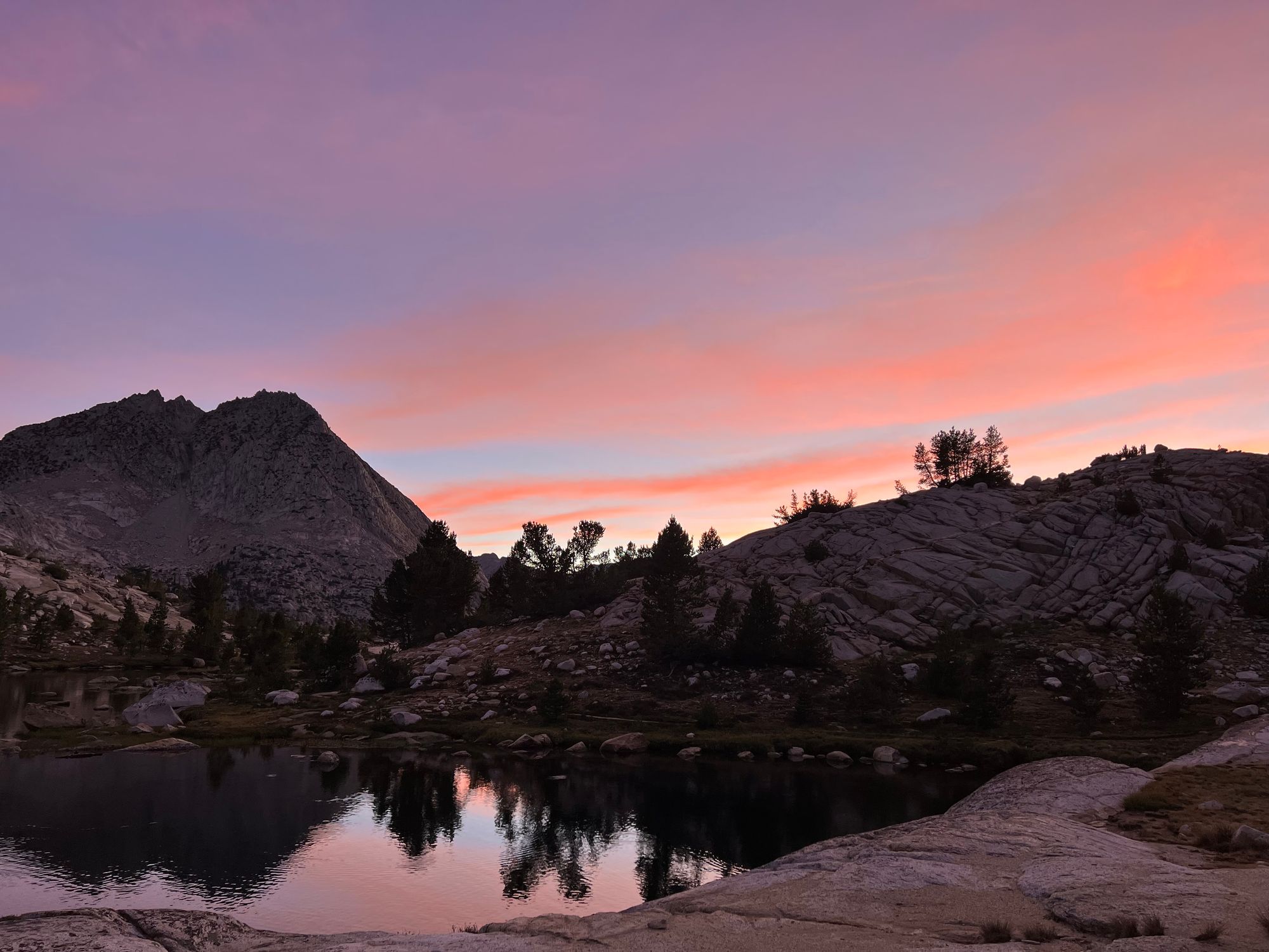 Orange-red clouds over mountains, getting reflected from a lake.