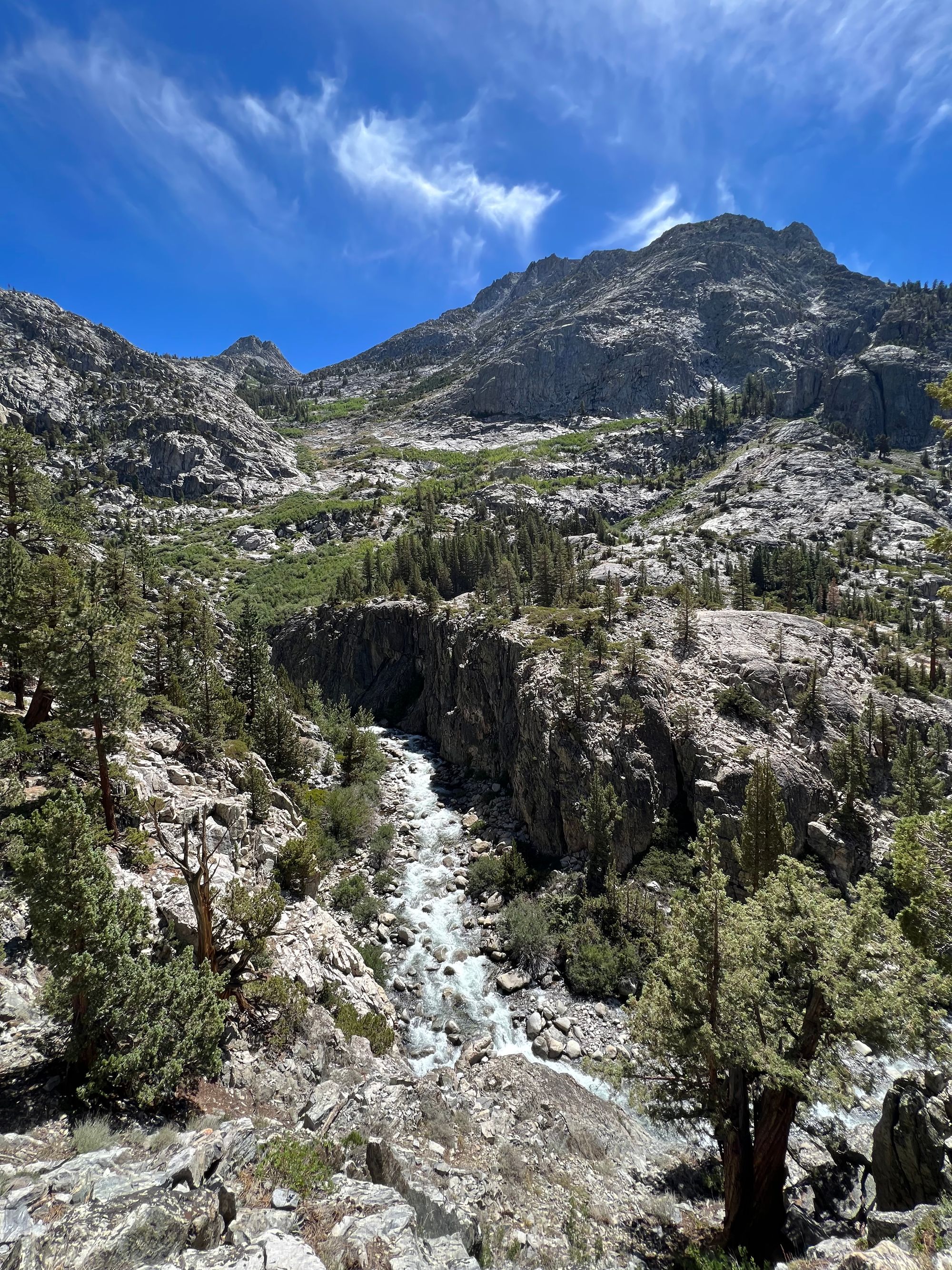 A creek flowing far below, with a tall rock wall on one side.