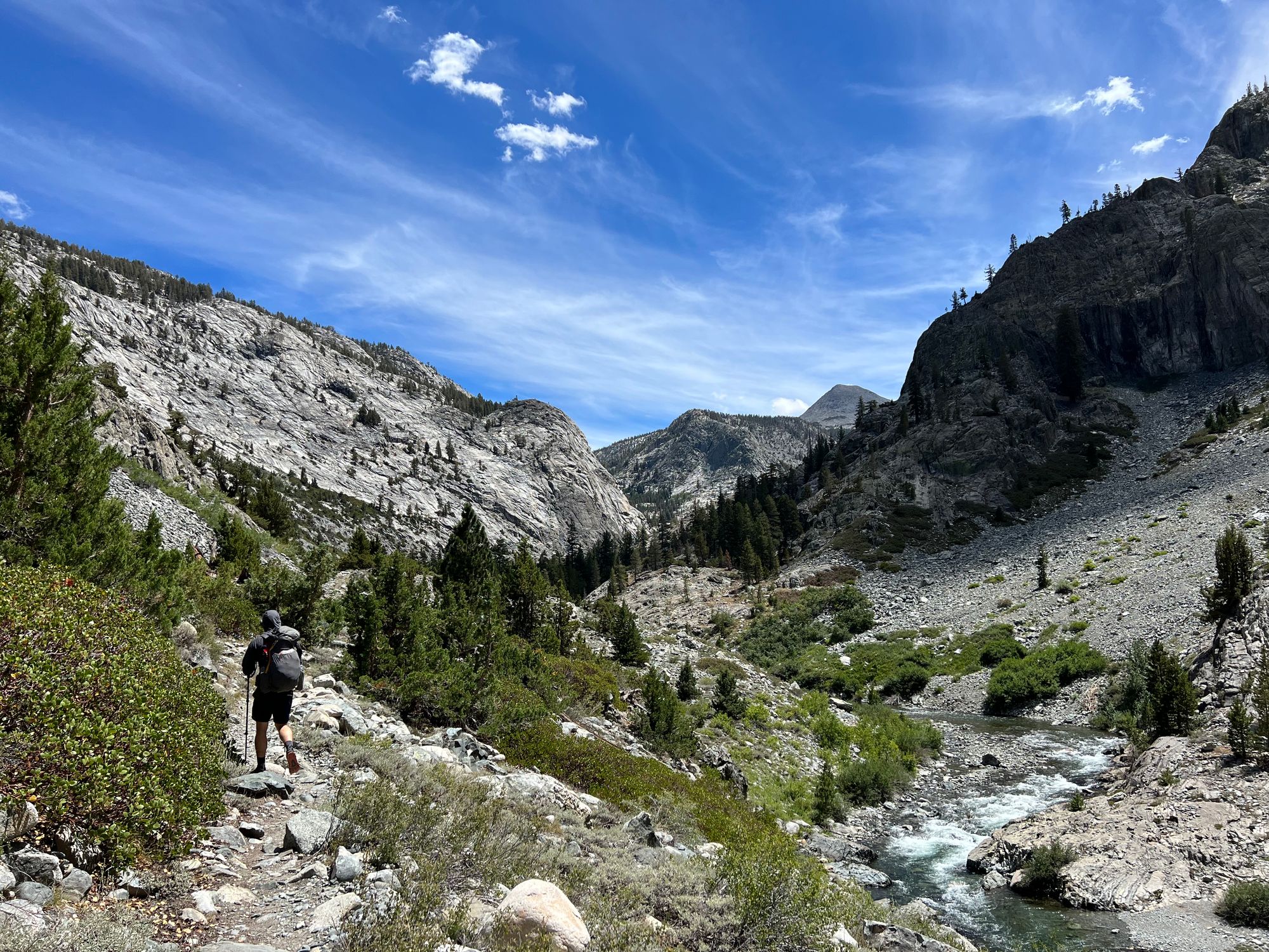 A backpacker walking along a creek.