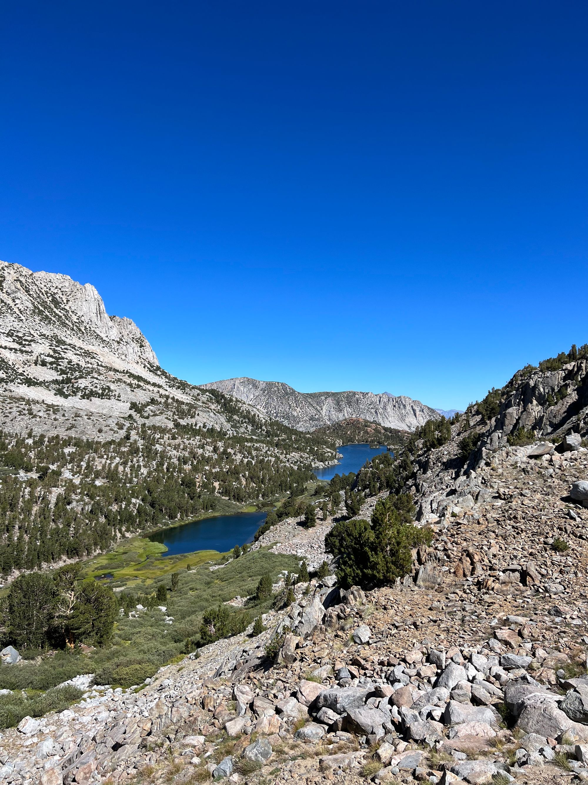 A creek running throug a meadow into a lake, which is connected to another lake further down.