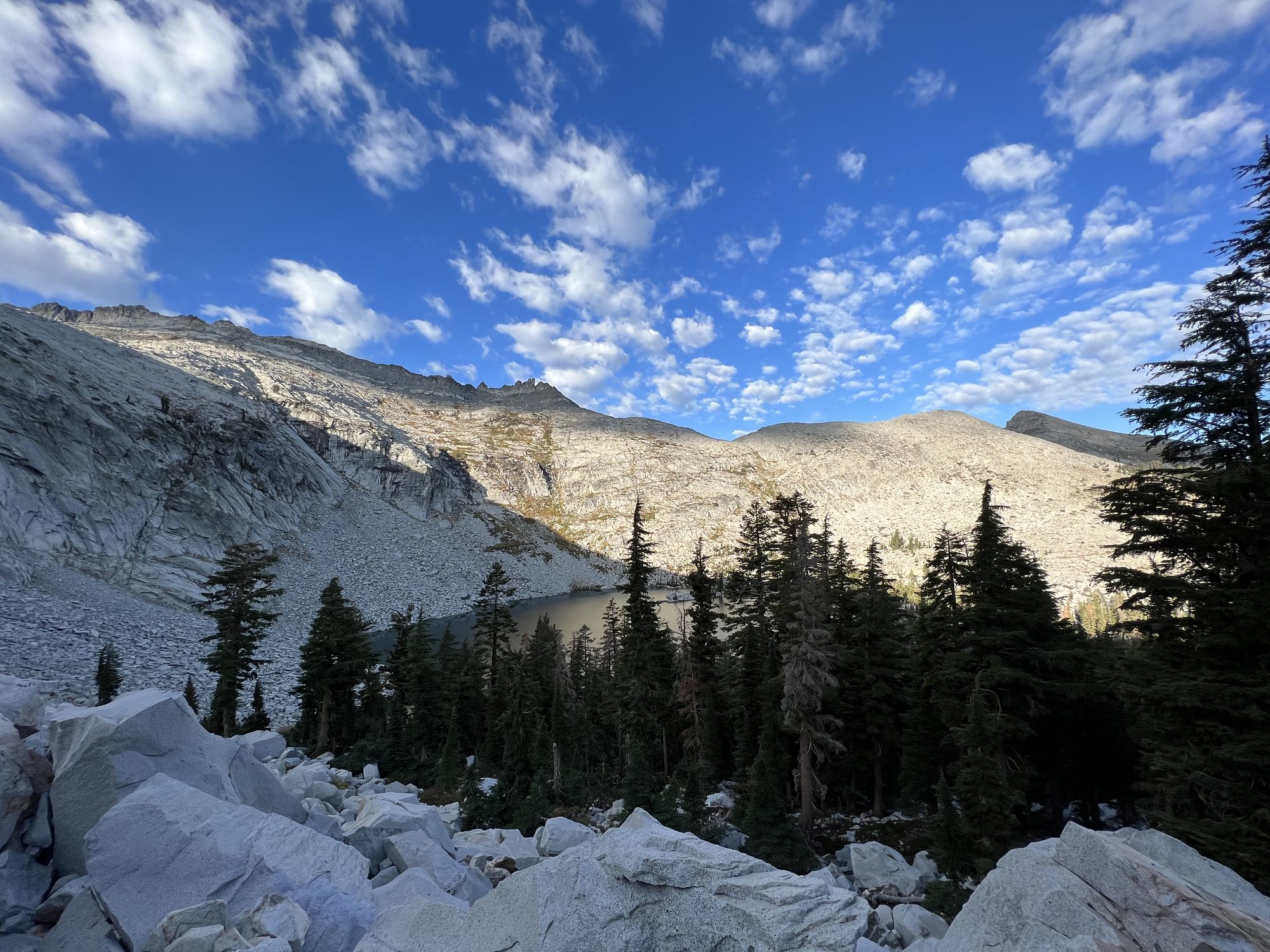 A lake surrounded by talus fields on one side, forest on the other.