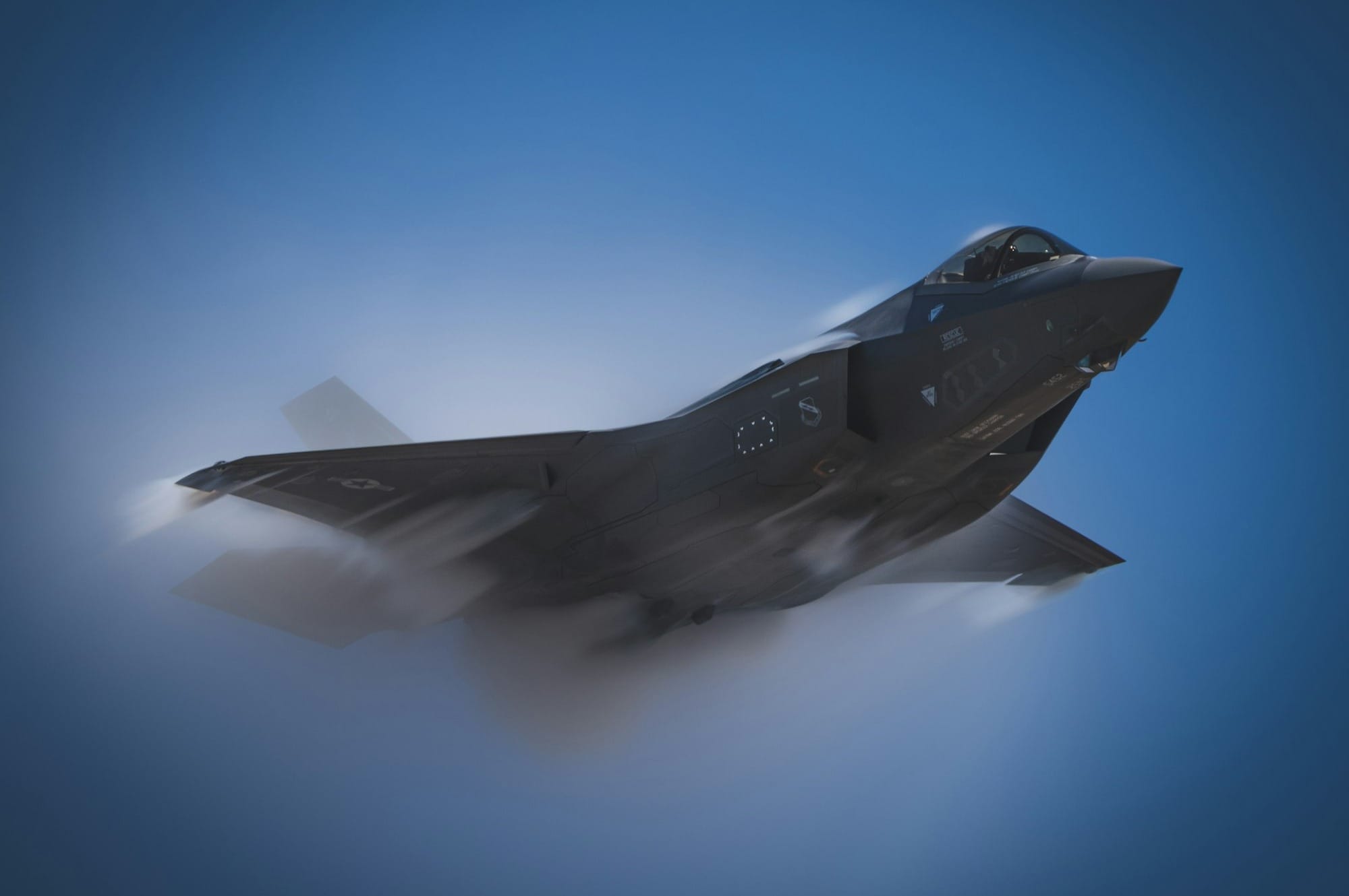 a fighter jet flying through a blue sky