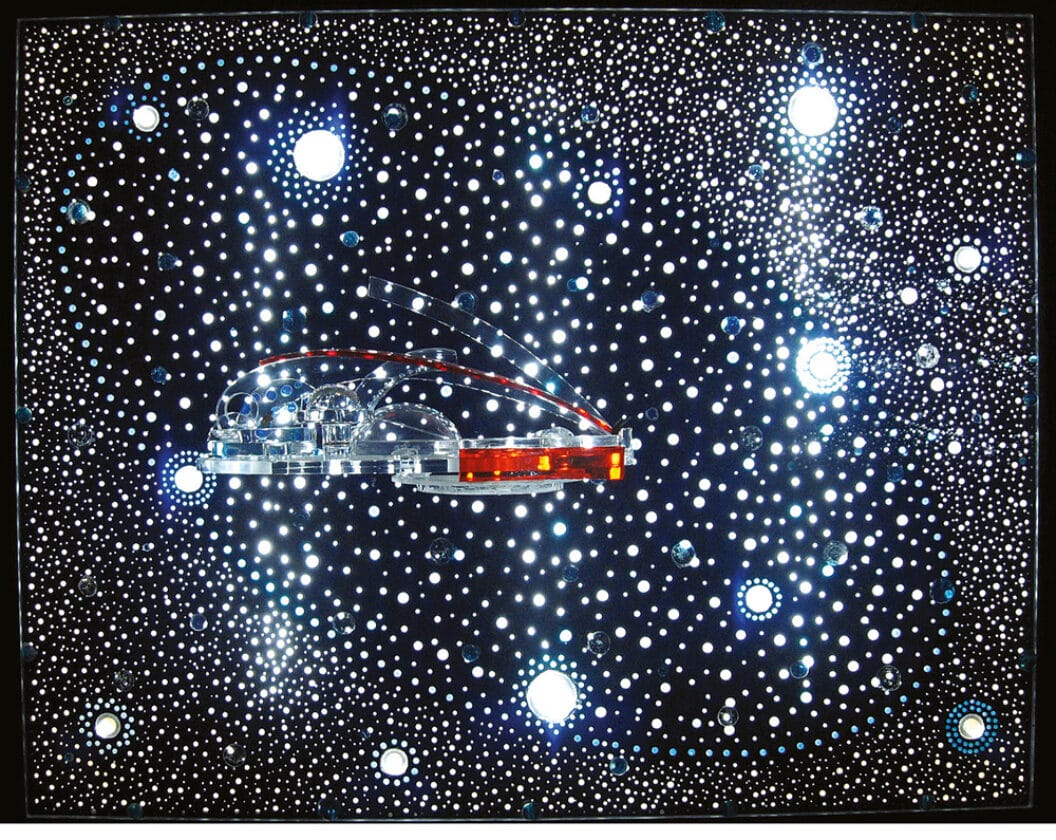 A sparkling glass plate with multiple holes that evoke stars and an odd contraption in the center.