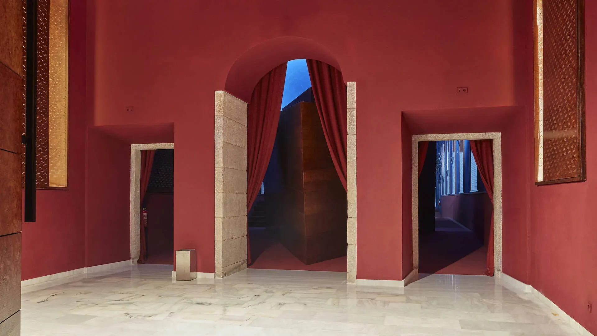 A cinema foyer, with red walls, and red curtains masking the main entrance.
