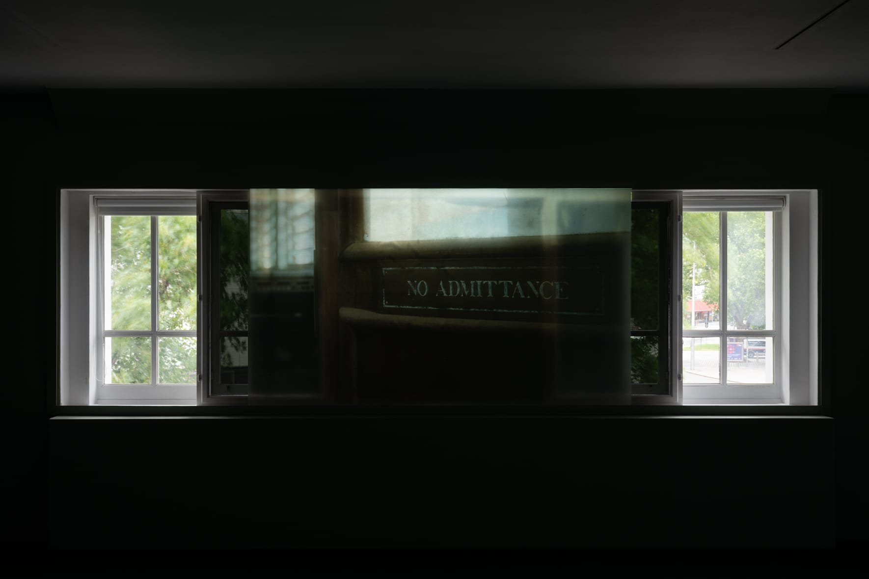 Videos projected onto the windowfront of a gallery, with one video image depicting a sign with the words "No Admittance" written on it.