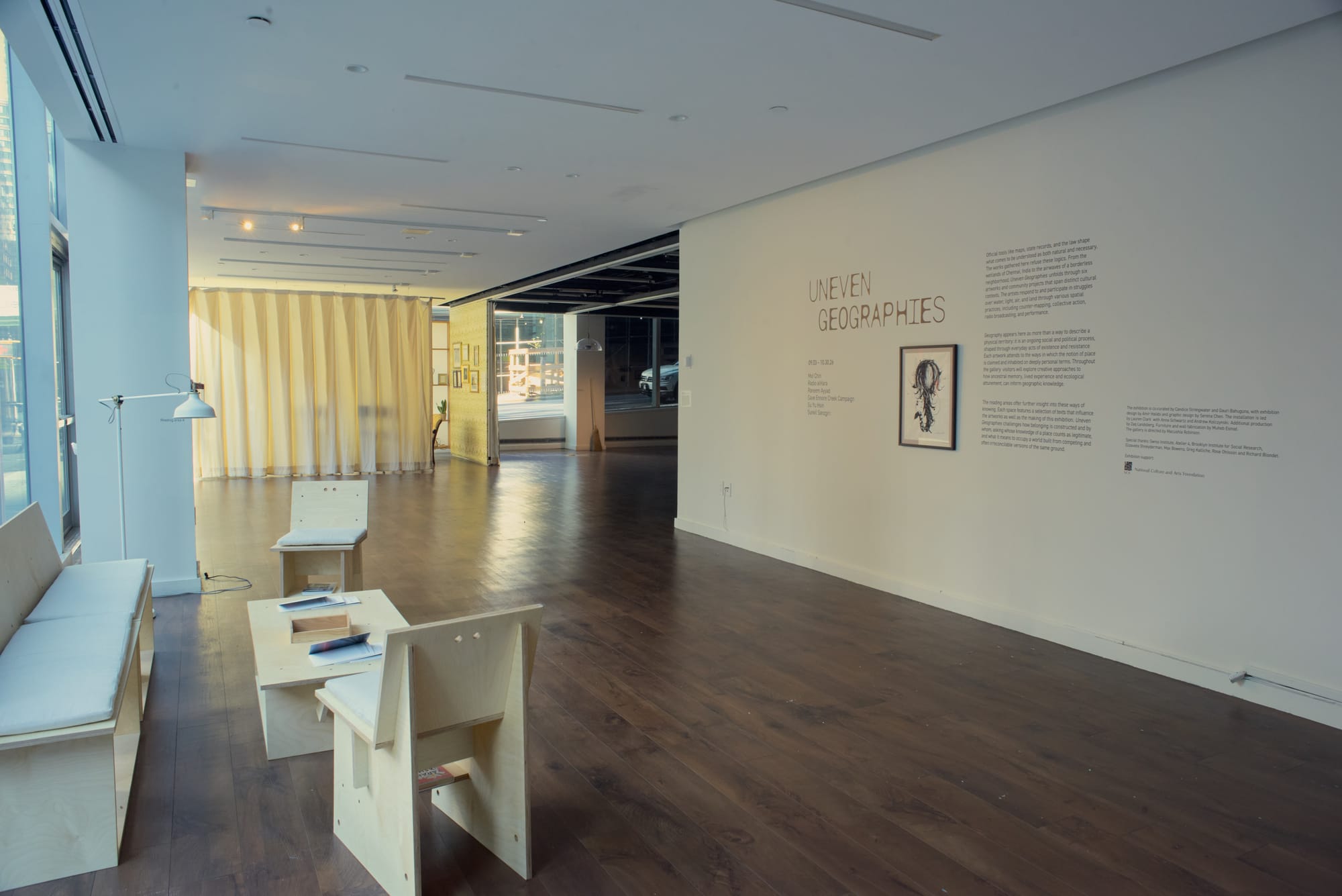 The entrance to a gallery space, with the exhibition title Uneven Geographies painted on the wall.