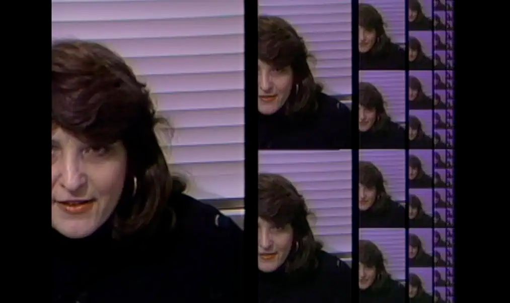 A woman with long brown hair and a dark shirt framed in a lo-fi video image that repeats in successively smaller sizes into infinity.