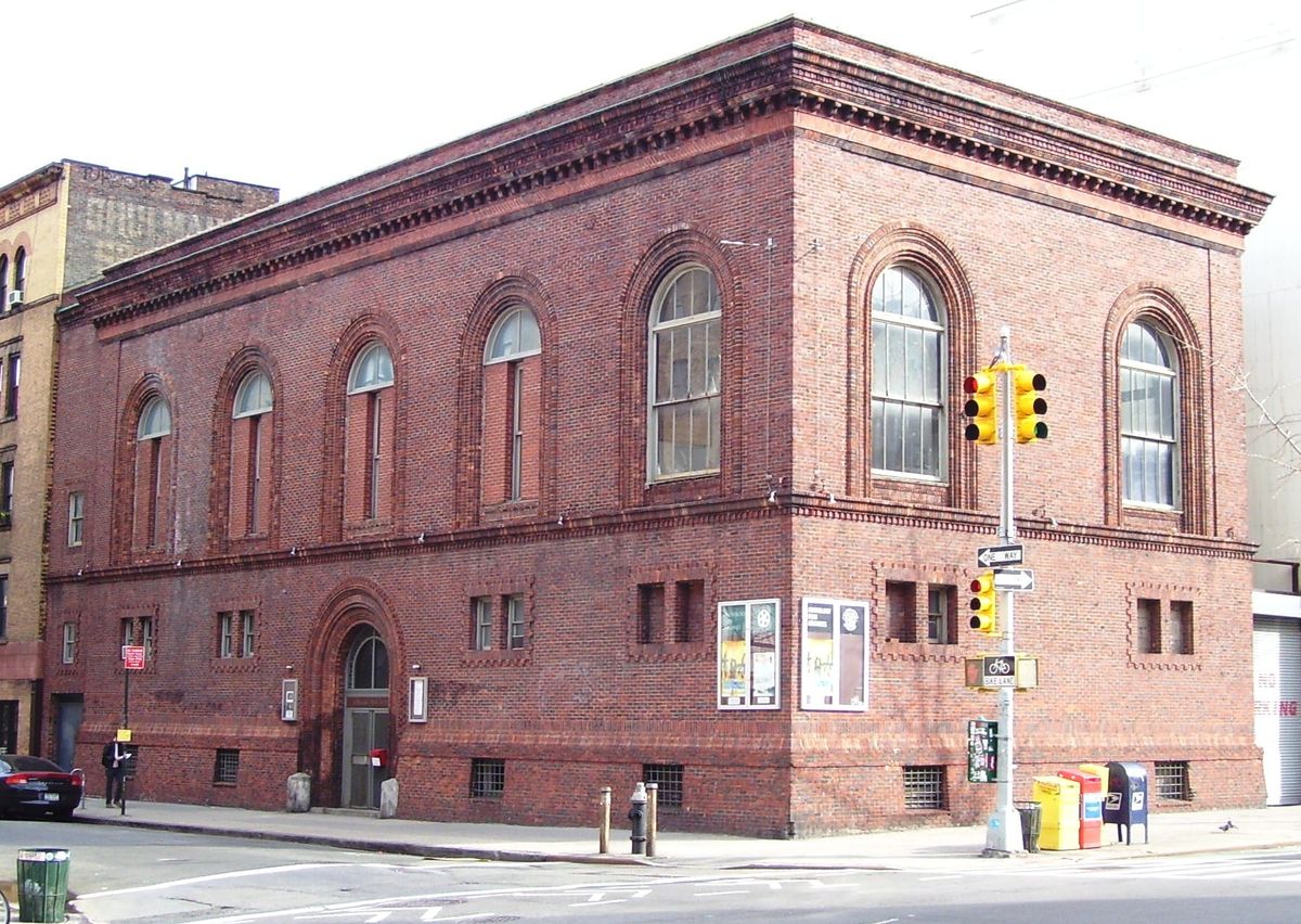 A grand red brick building on an urban city street.