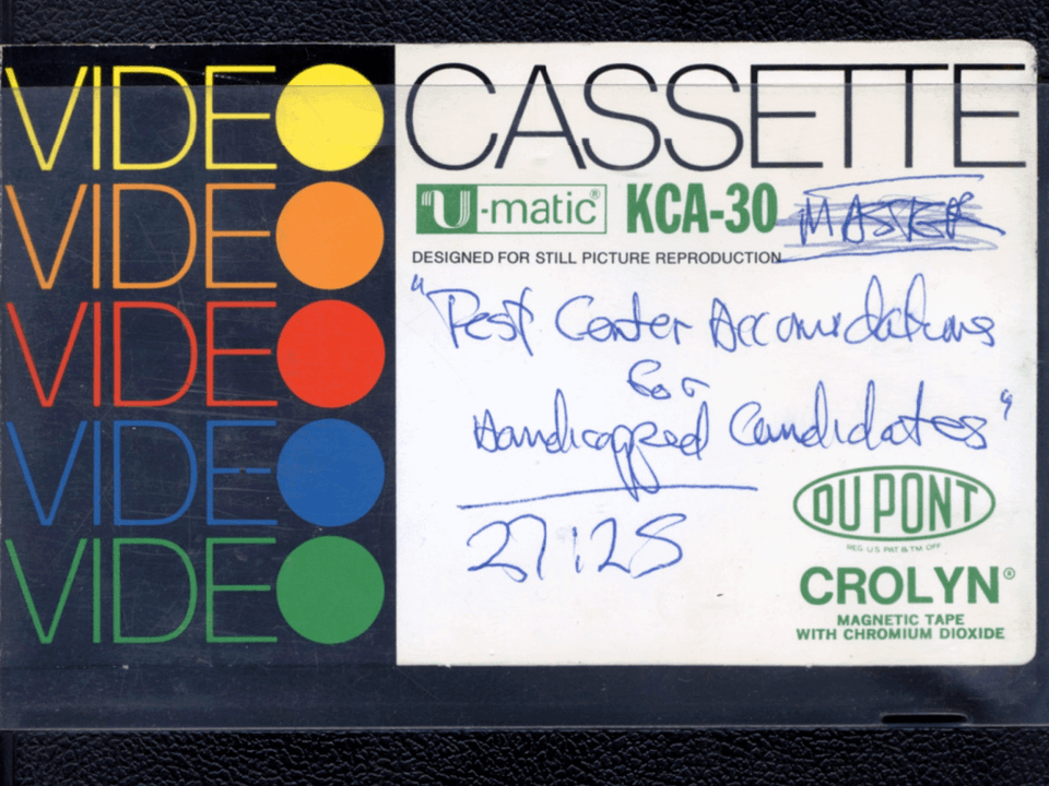 A three-quarter inch U-matic video cassette with a colorful, hand-written label.