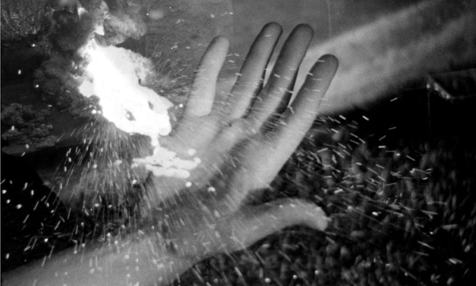 A black and white image of a hand with sparks superimposed over it.
