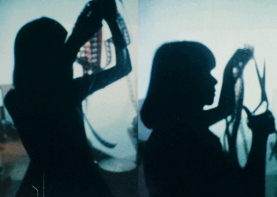 An image in two halves, similar but with slight variations, with a woman in shadows holding film strips up to the light, and she is holding scissors in the second image.