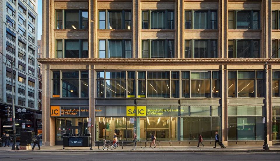 A large building with glass windows on a busy urban street, with the logo for School of the Art Institute of Chicago placed above the main entrance.