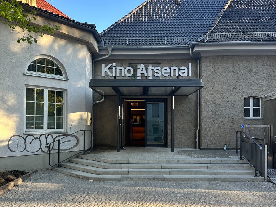 A nondescript concrete building with the words Kino Arsenal printed on a marquee above the front doors.
