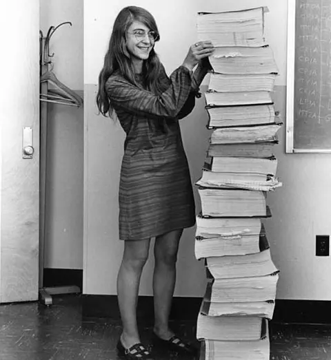 Margaret Hamilton next to the printed out code of the Apollo 11 flight computer. The paper tower is as tall as herself.