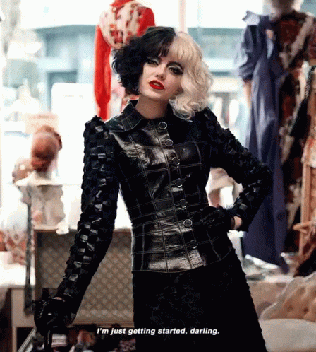 Emma Stone in Cruella. Standing in a dress store dressed in full black, with a cane, saying "I'm just getting started, darling."