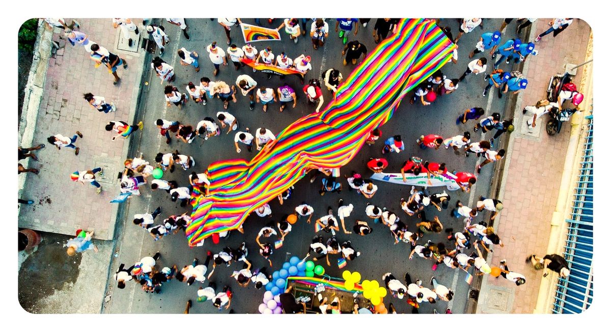 an overhead shot of a pride parade filled with rainbow flags and balloons