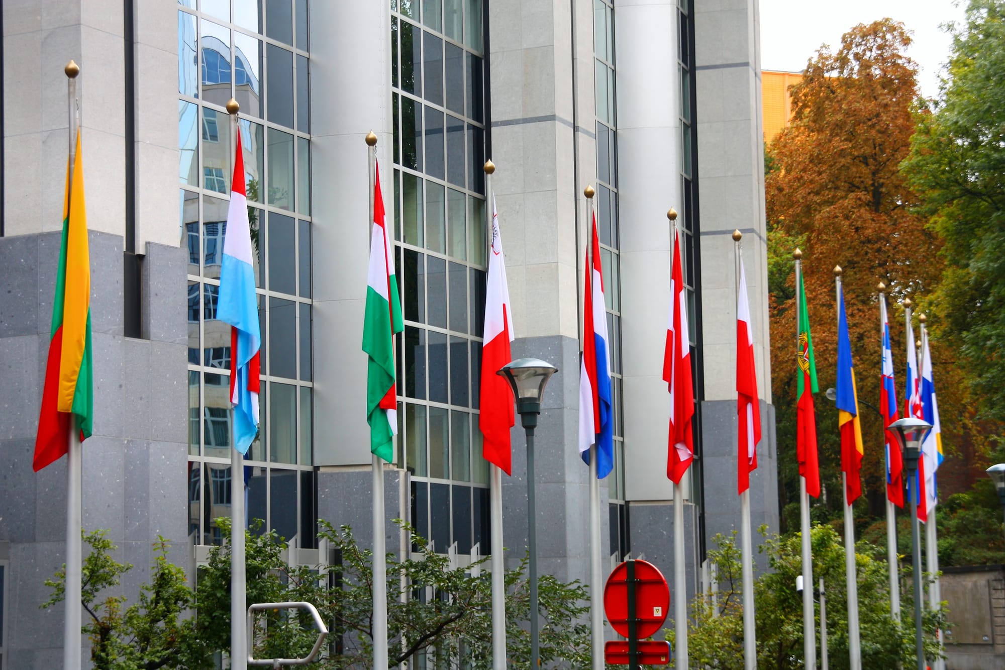 Member-state flags arrayed in front of the European Parliament in Brussels — the institutional surface on which national implementation of the AI Act now sits.
