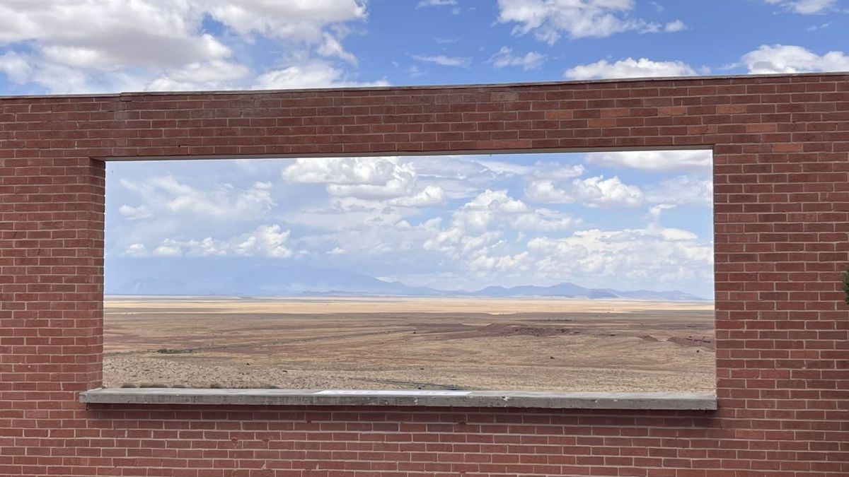 A window in a red brick wall at Meteor Crater provides a view from across the desert to the distant San Francisco Peaks of Flagstaff, Arizona