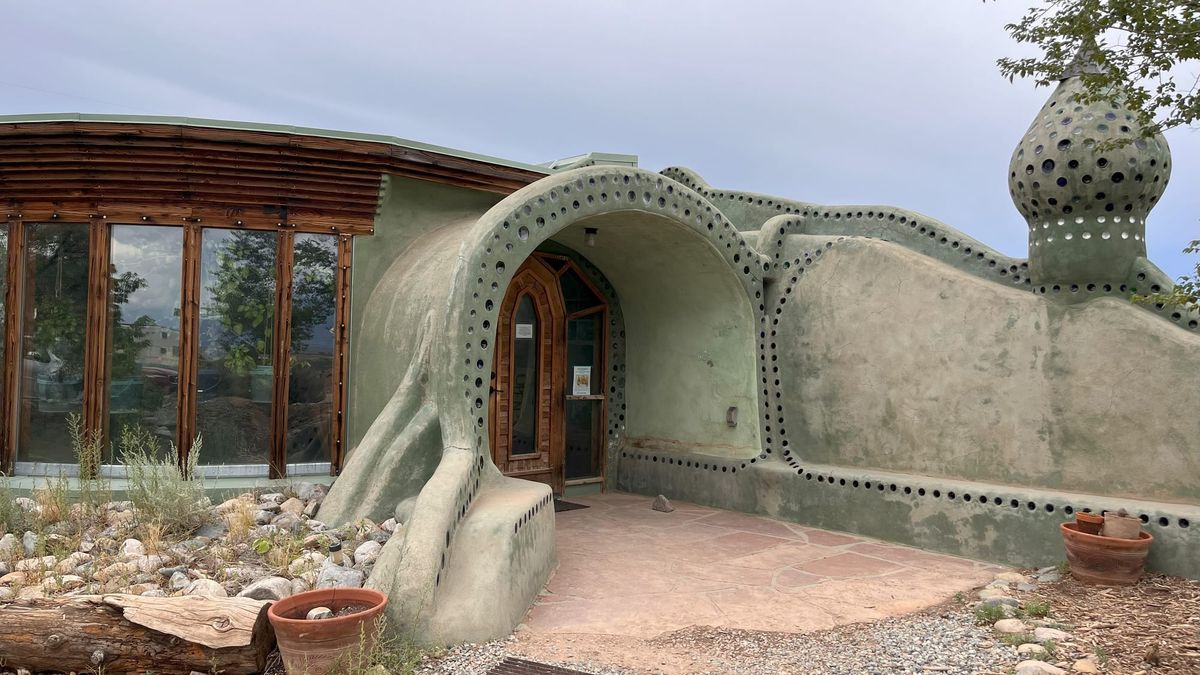 Green stucco and brown wood at the entrance of a rammed-earth brick style house
