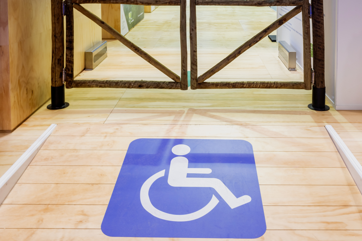 White on blue wheelchair symbol on the surface of a wooden ramp leading to a swing gate exit