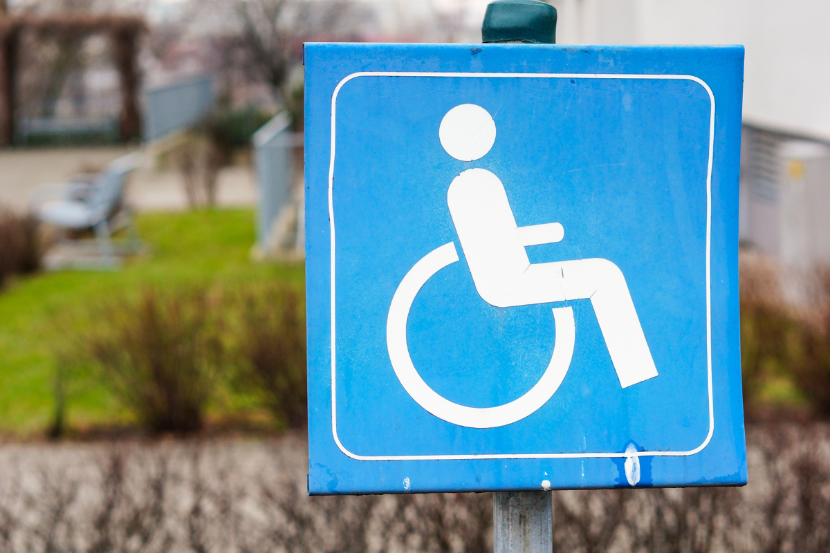 White on light blue wheelchair symbol on a vertically posted outdoor sig